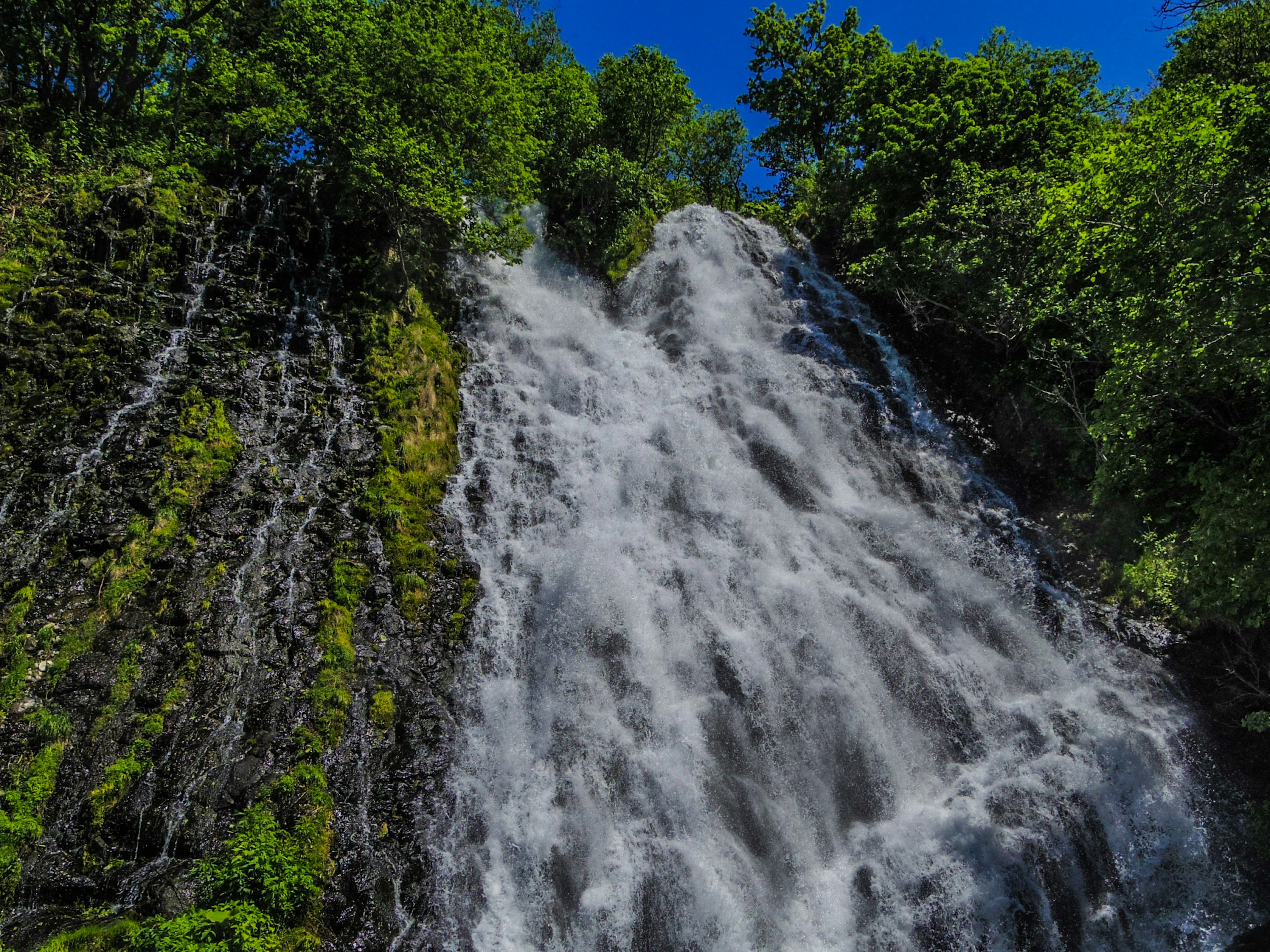 Ein schöner Wasserfall umgeben von Grün mit spritzendem Wasser