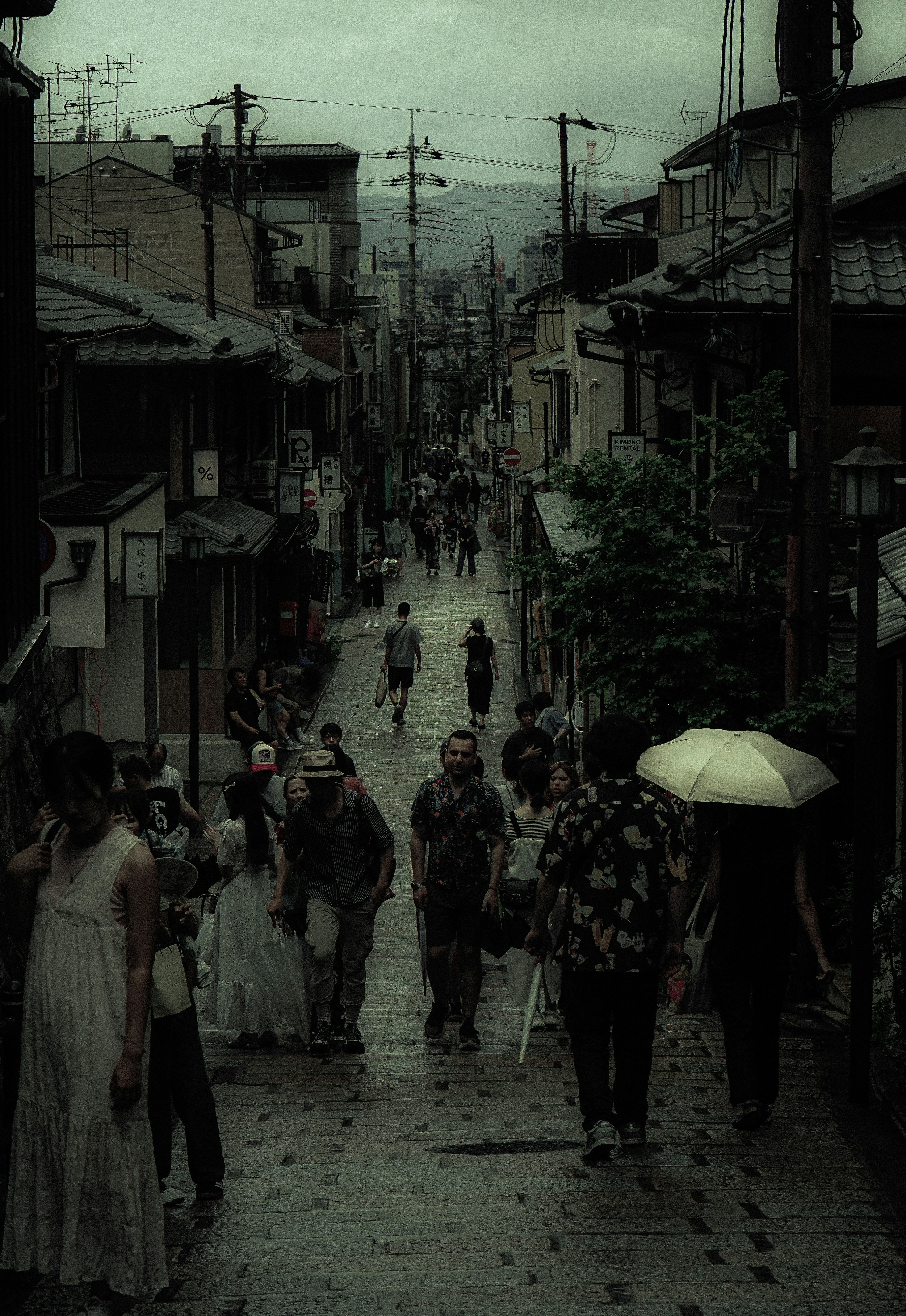 Una escena callejera con personas caminando bajo la lluvia en un viejo pueblo