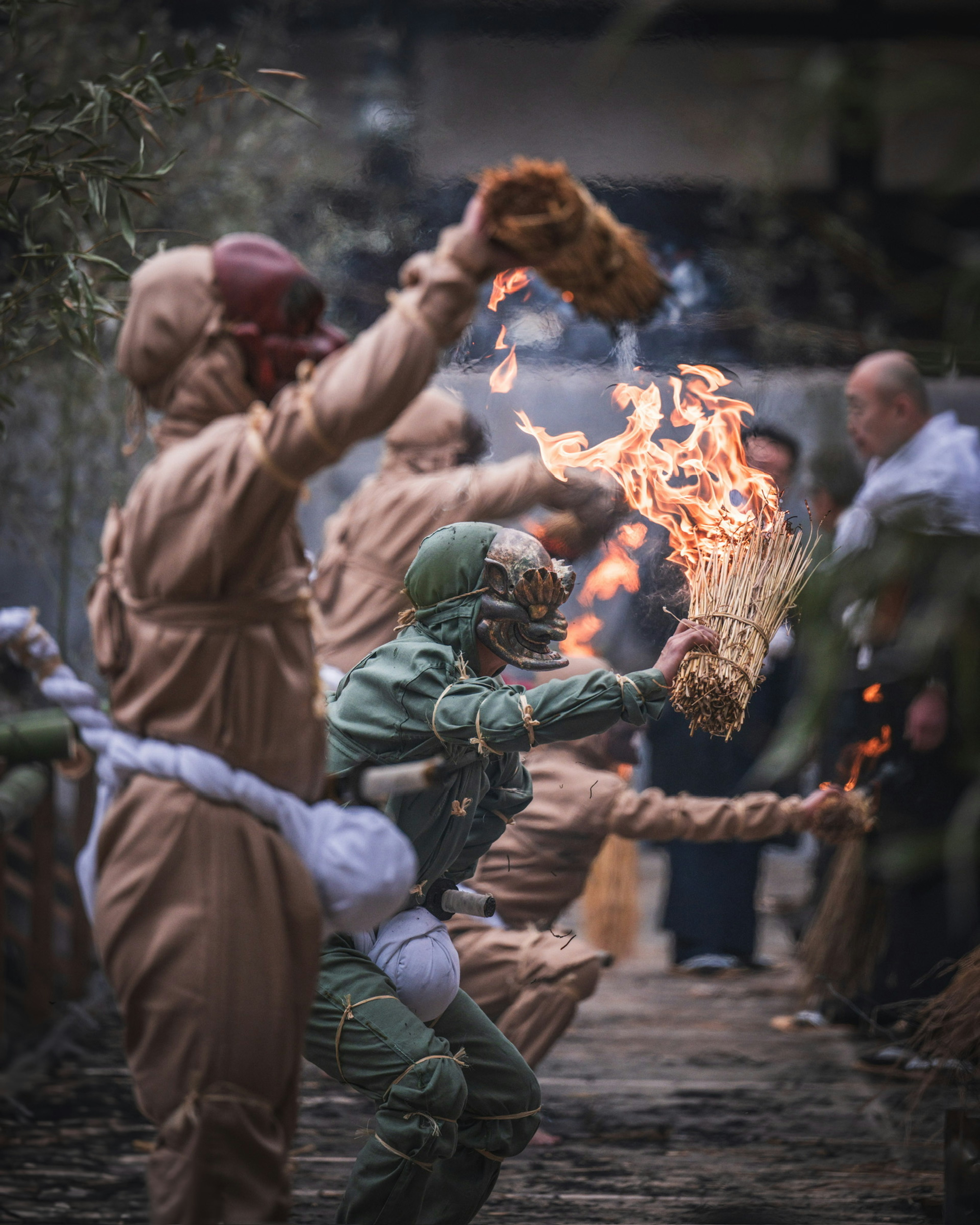 Teilnehmer in traditionellen Kostümen halten Feuer während eines Festivals