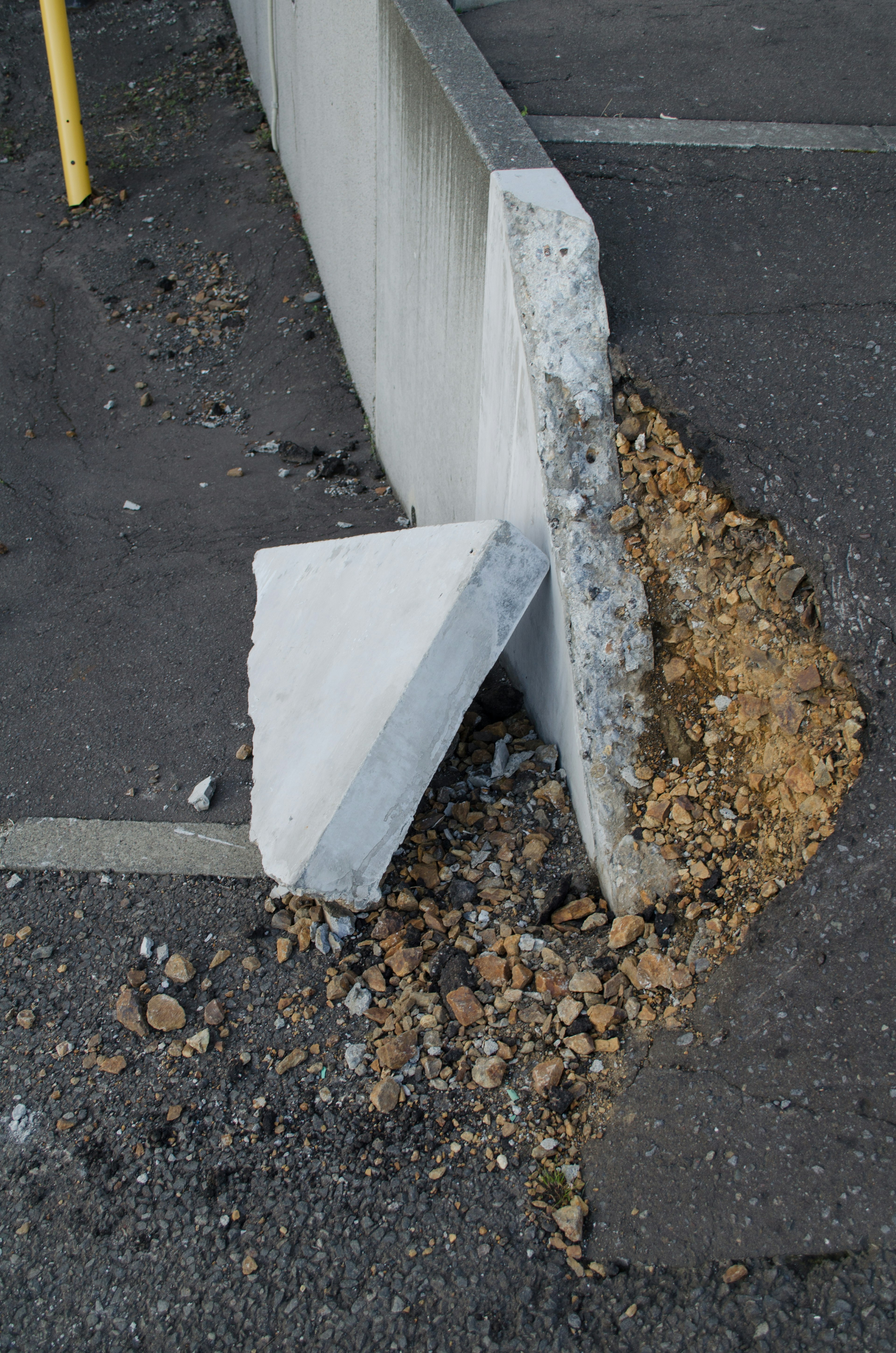 Mur en béton endommagé avec des gravillons autour