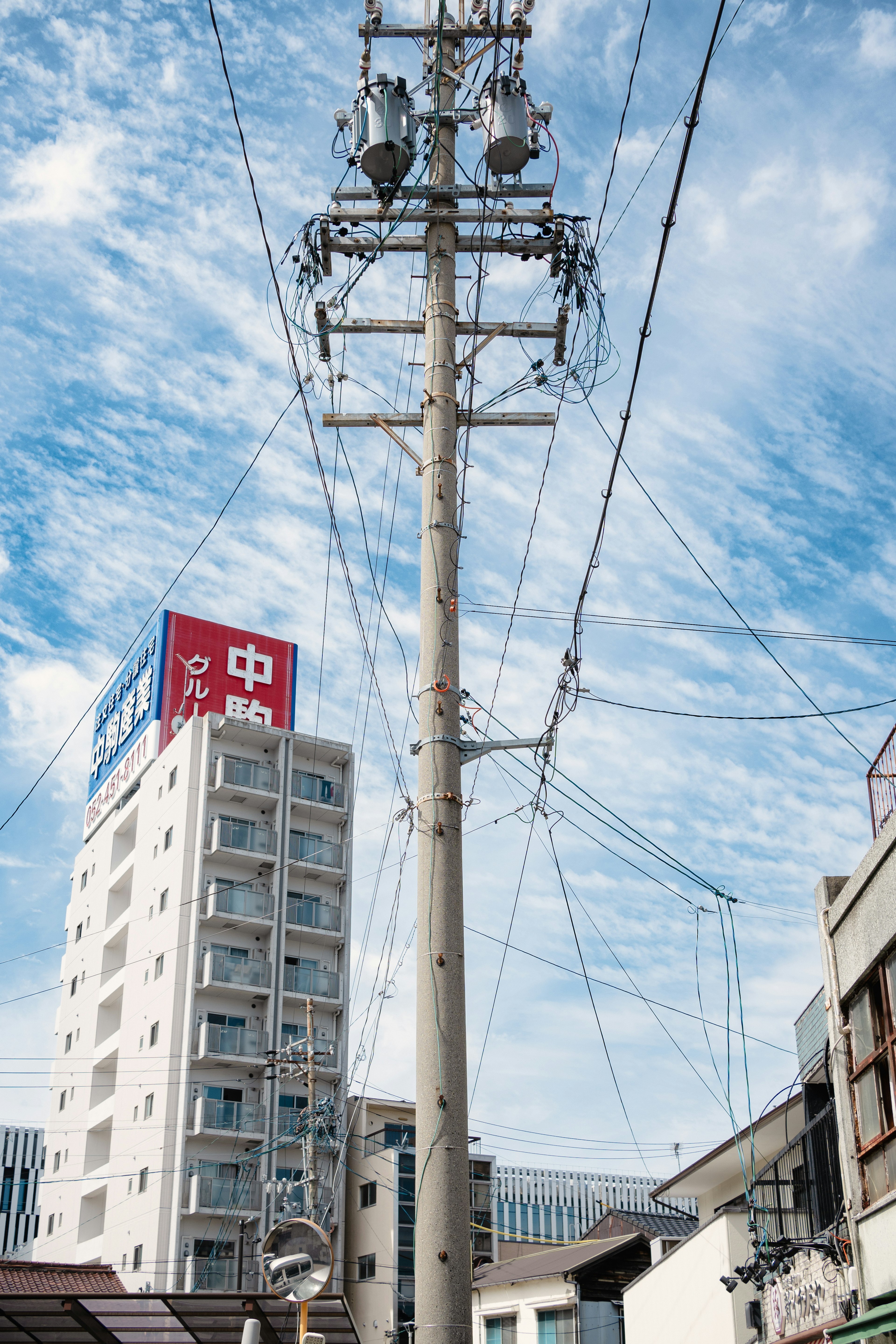 高い電柱と青い空の下にあるビルの風景