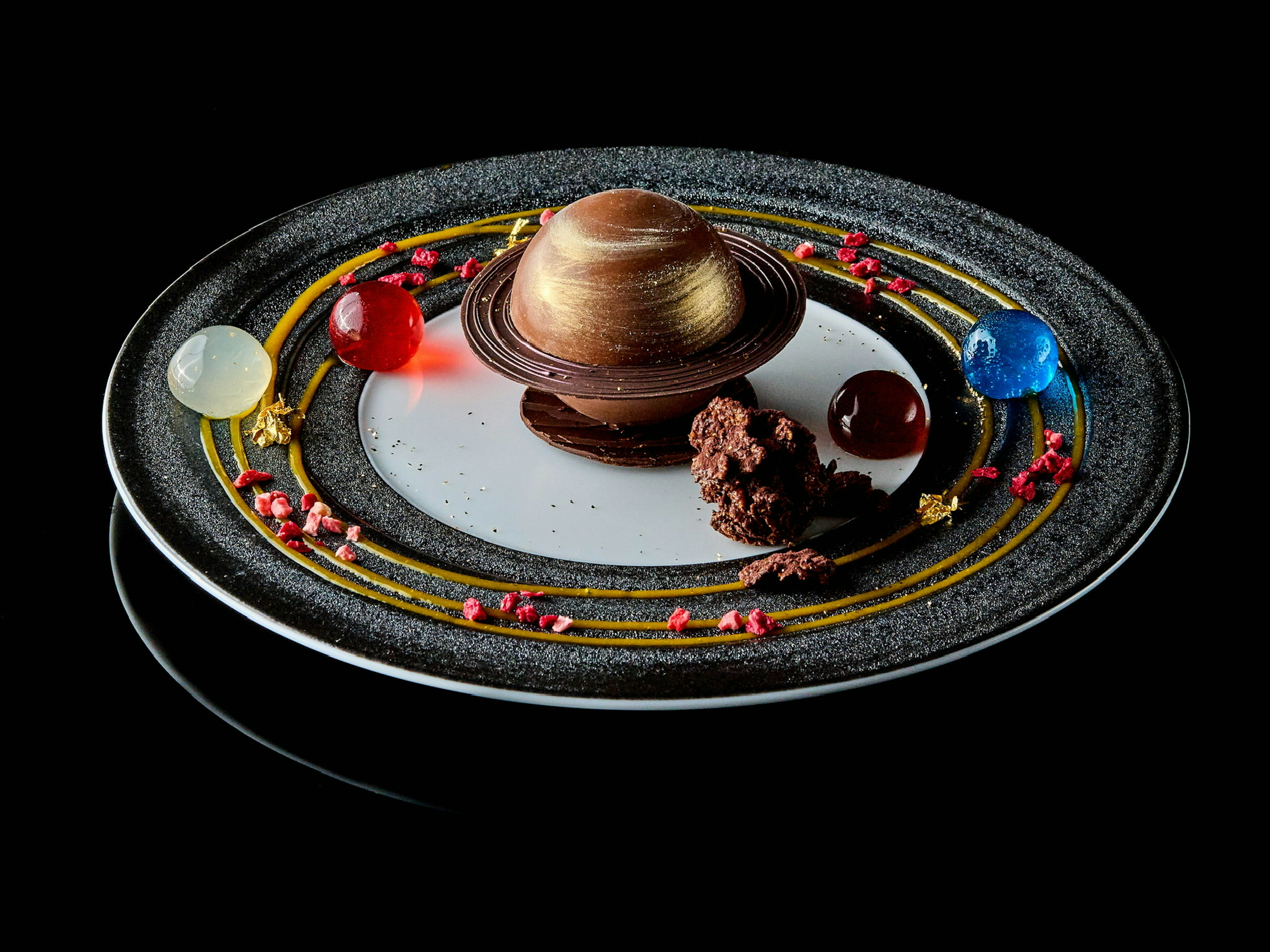 Postre en forma de planeta en un plato con decoraciones de caramelos coloridos