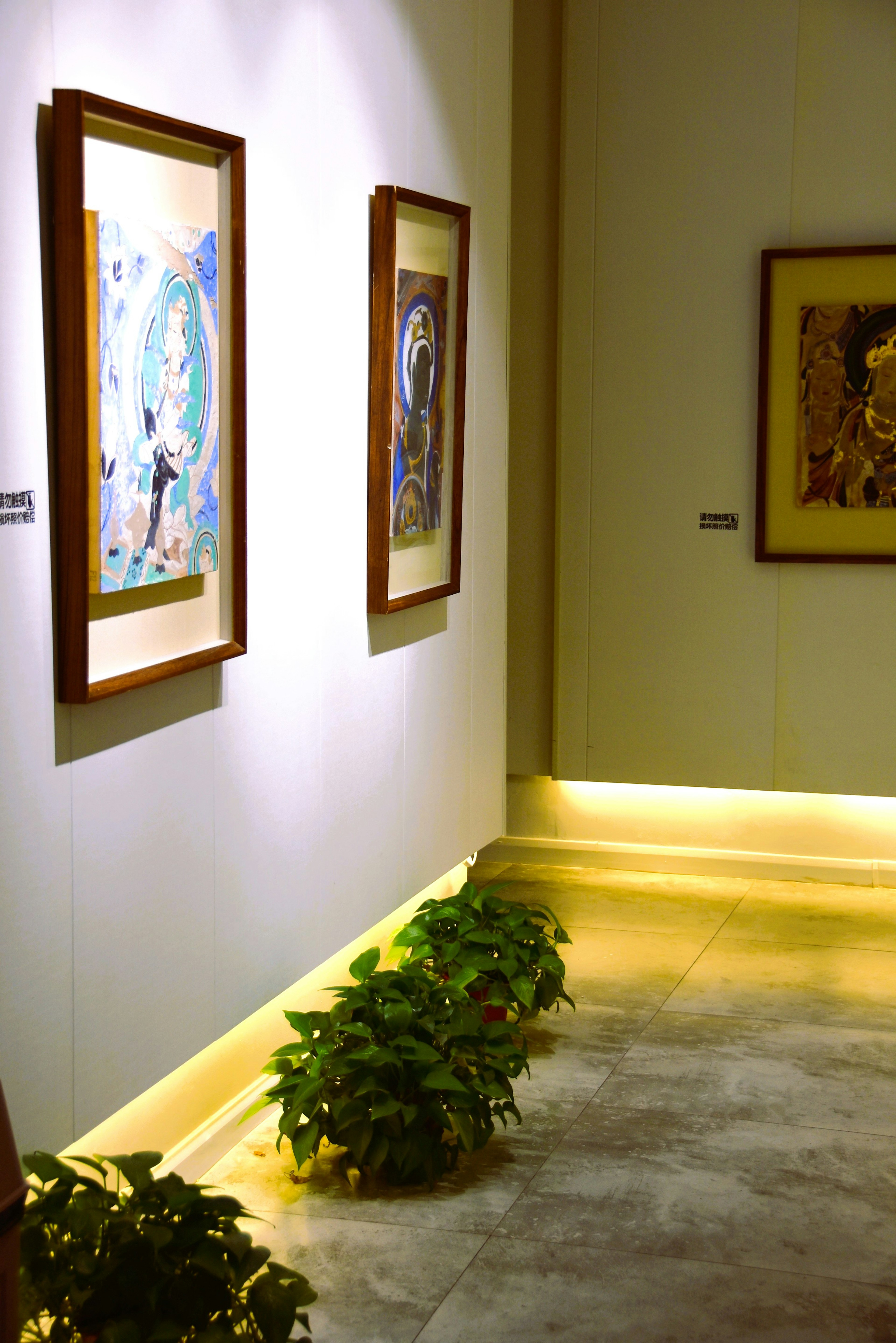 Gallery with two paintings on the wall and soft lighting