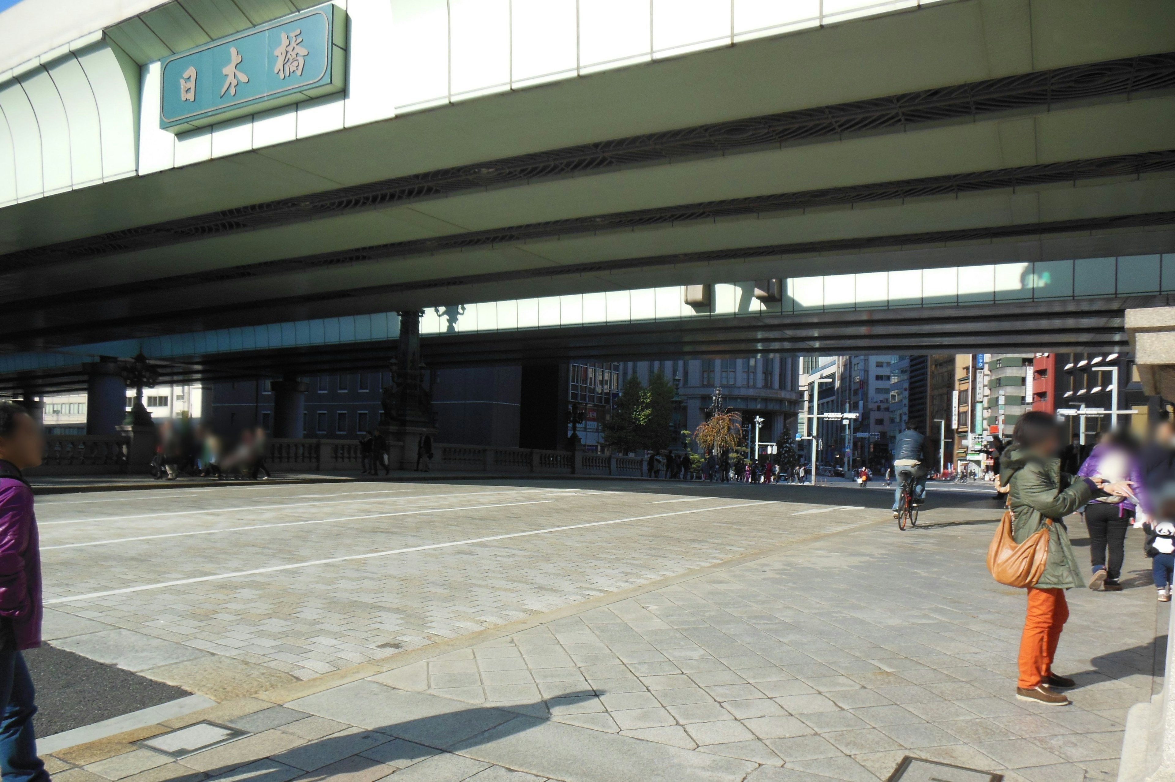 Open plaza under an overpass with pedestrians