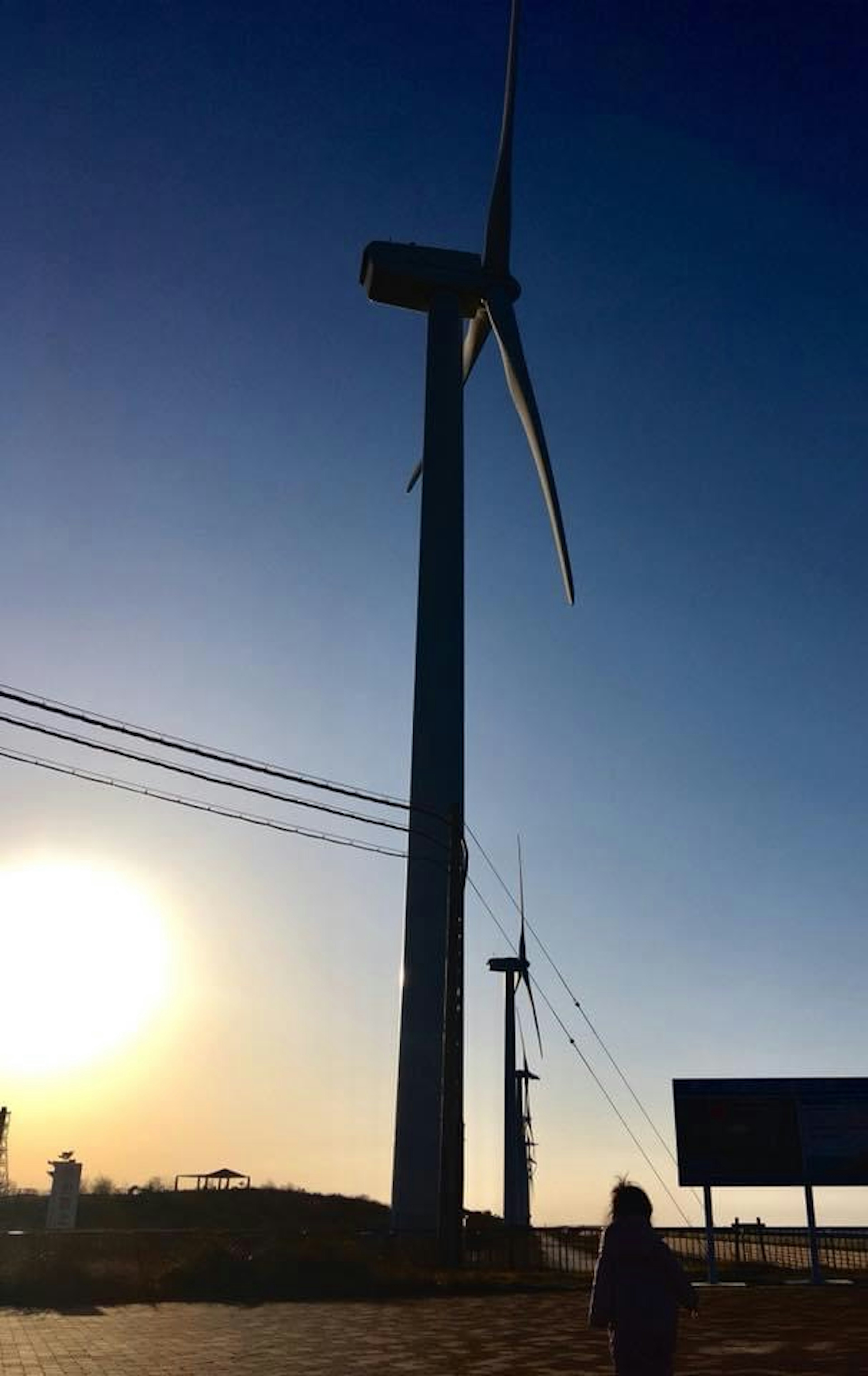 風力発電機と夕日のシルエットが美しい風景