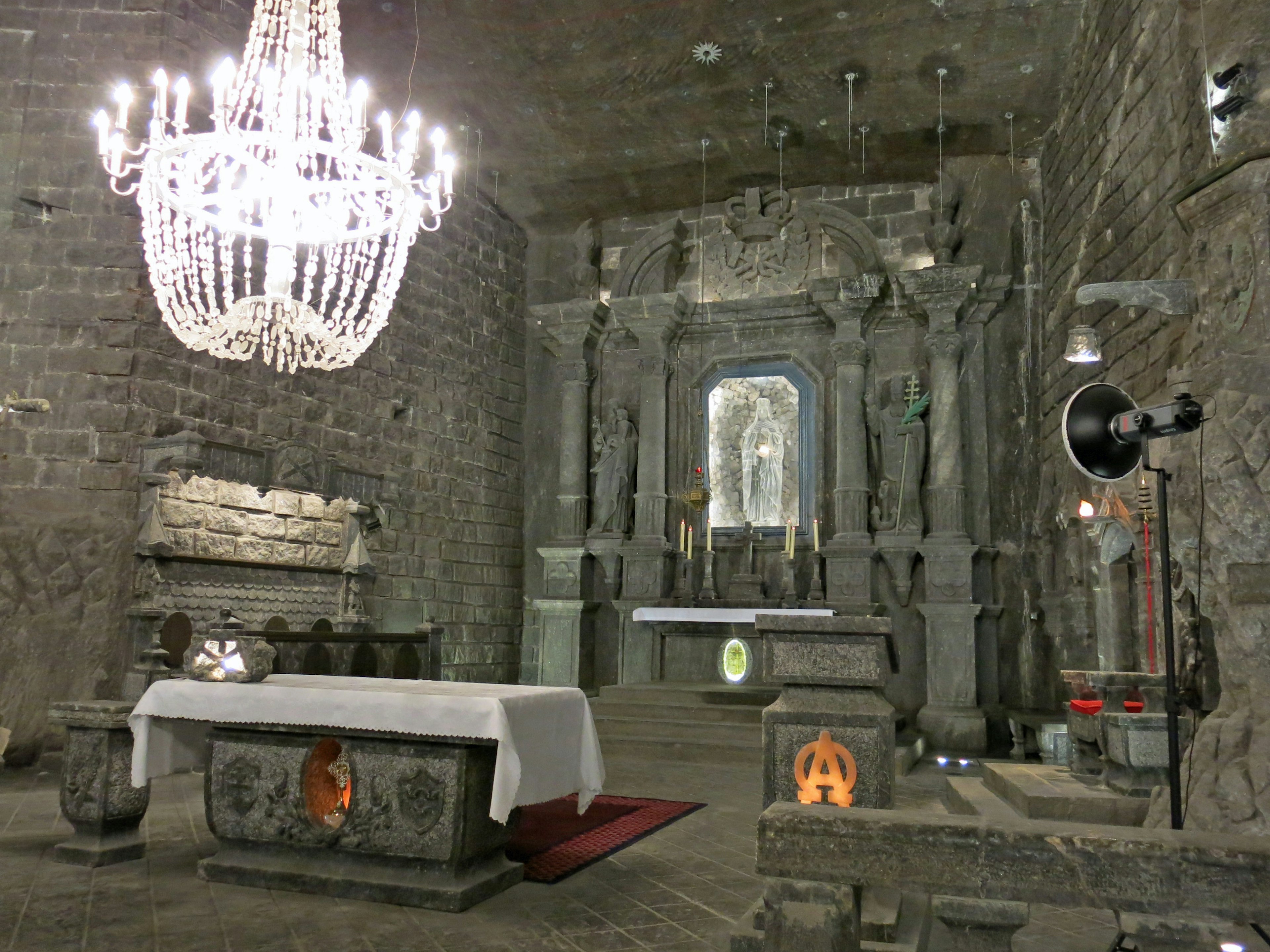 Interior of a stone church featuring an ornate chandelier and altar