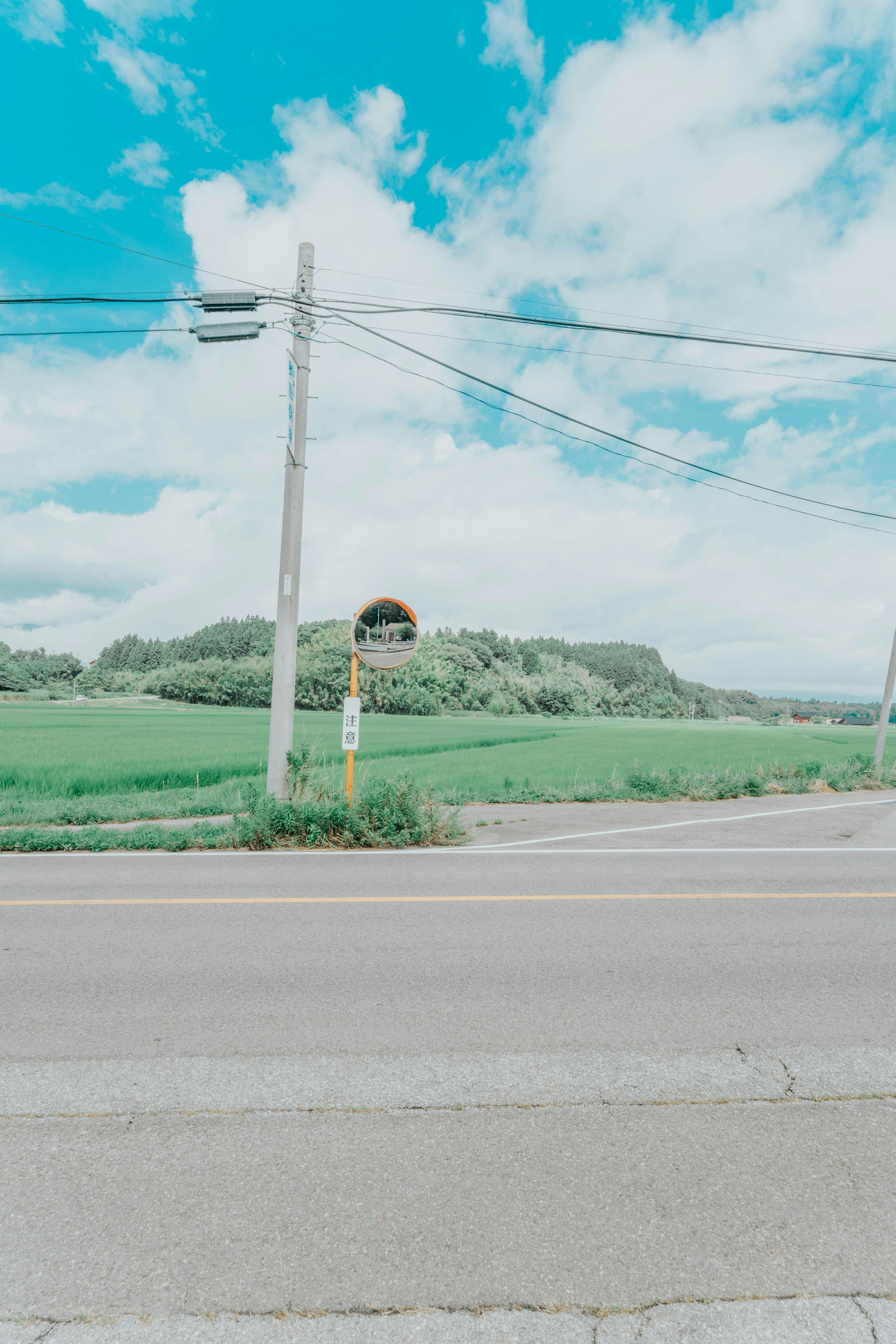 Parada de autobús con paisaje verde bajo un cielo azul y nubes blancas