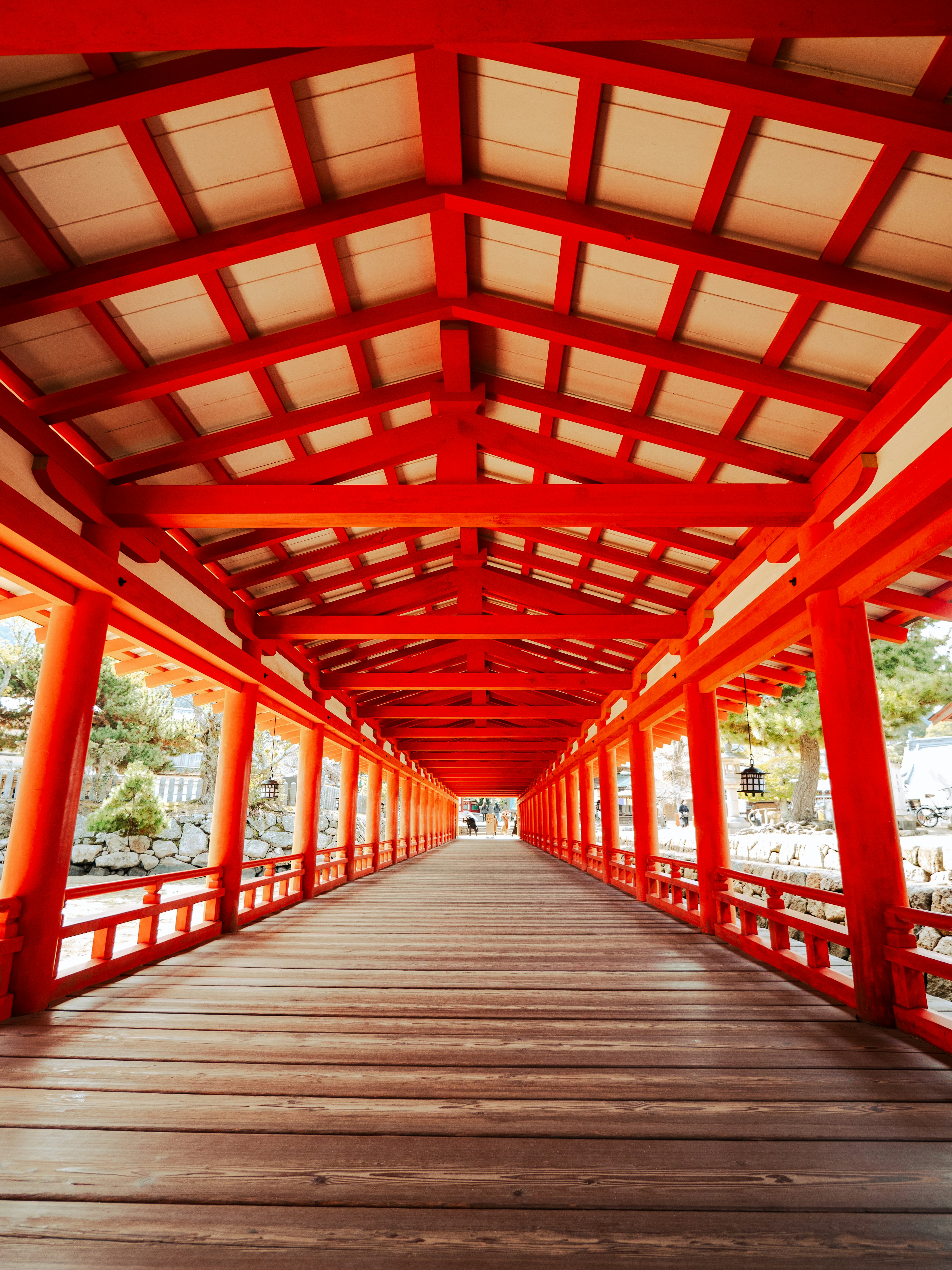 Vista interior de un puente rojo, suelo de madera, techo enrejado, luz brillante