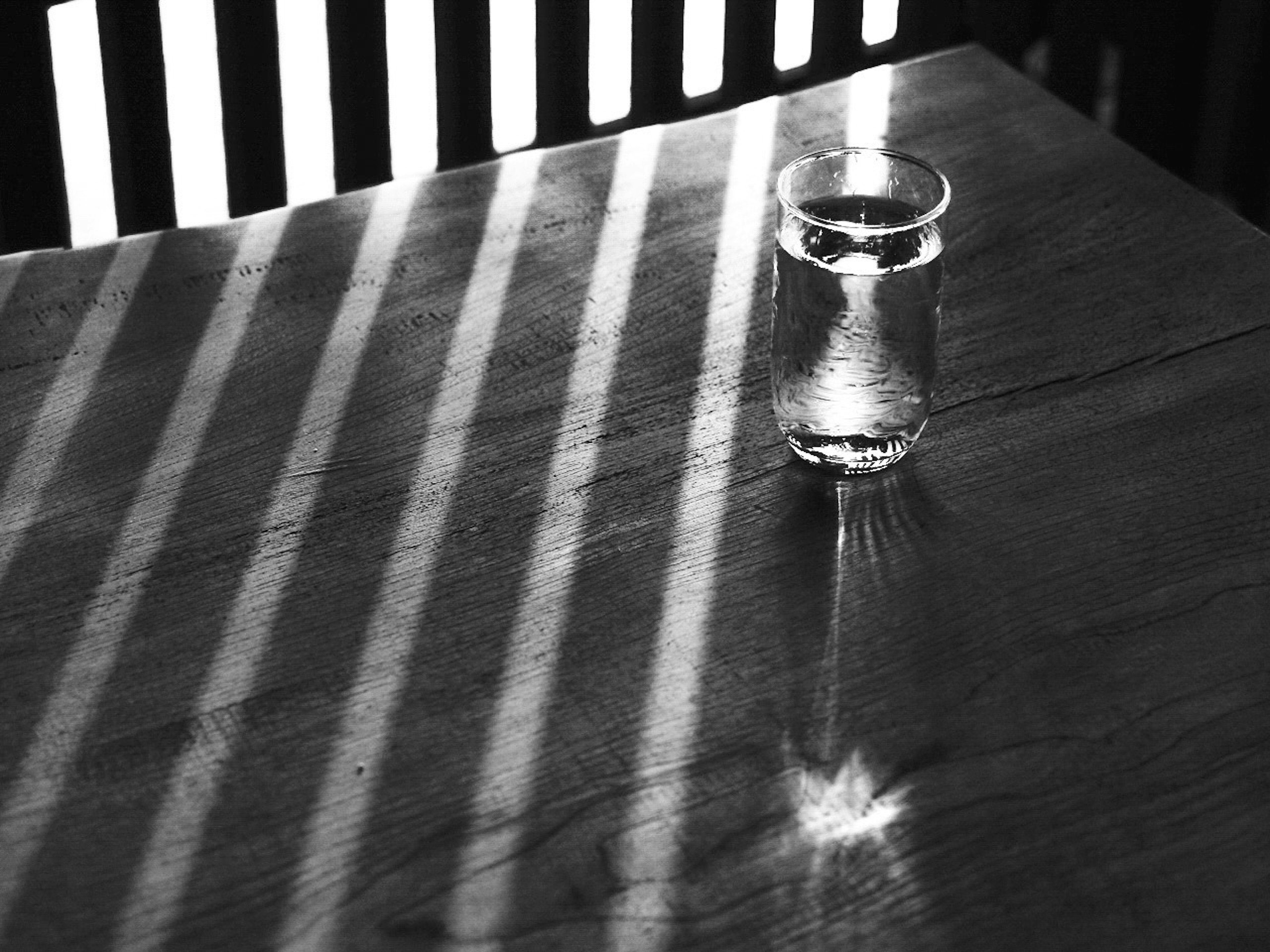 Transparent glass on wooden table with light stripes