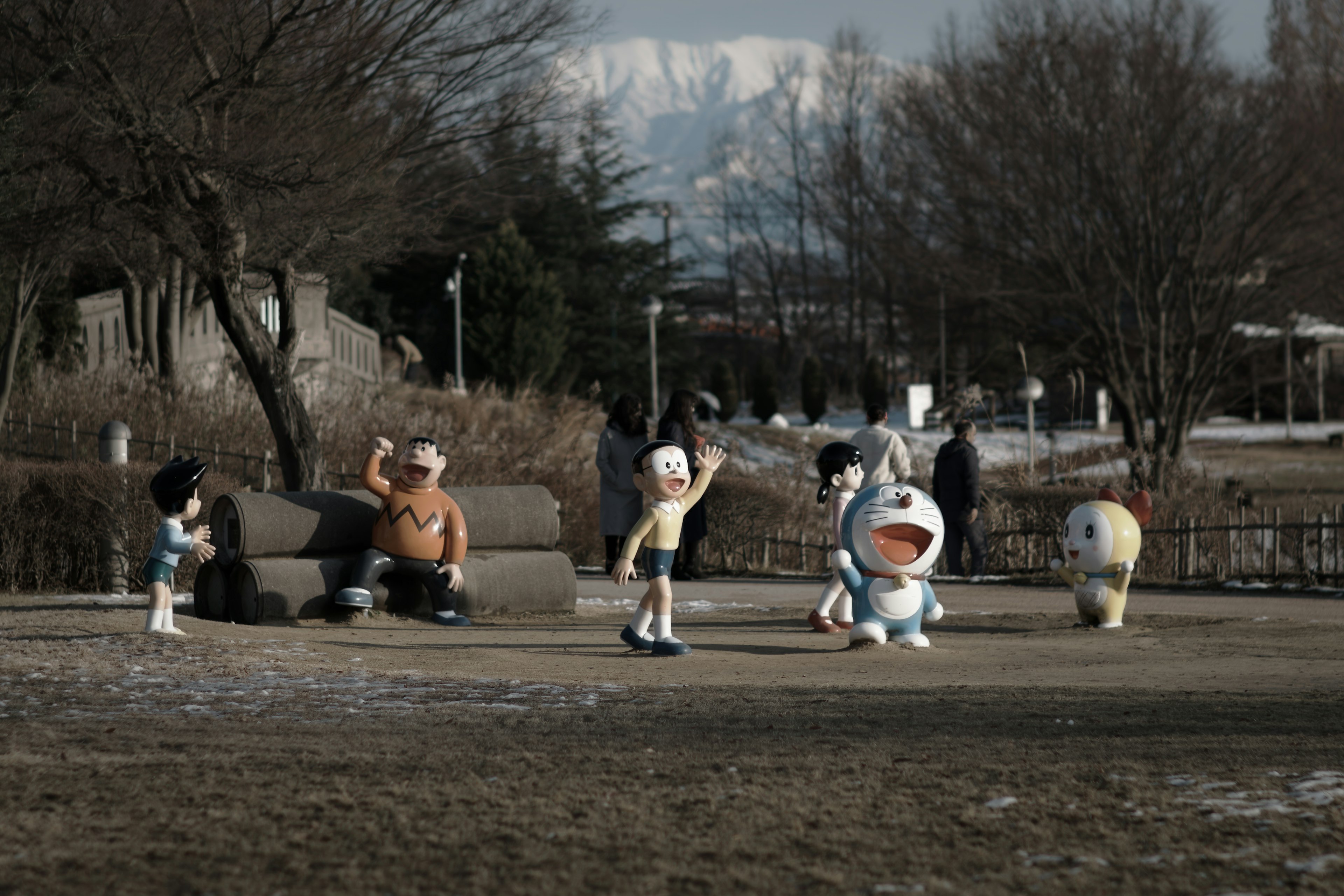 Scene in a park with characters playing and snow-capped mountains in the background