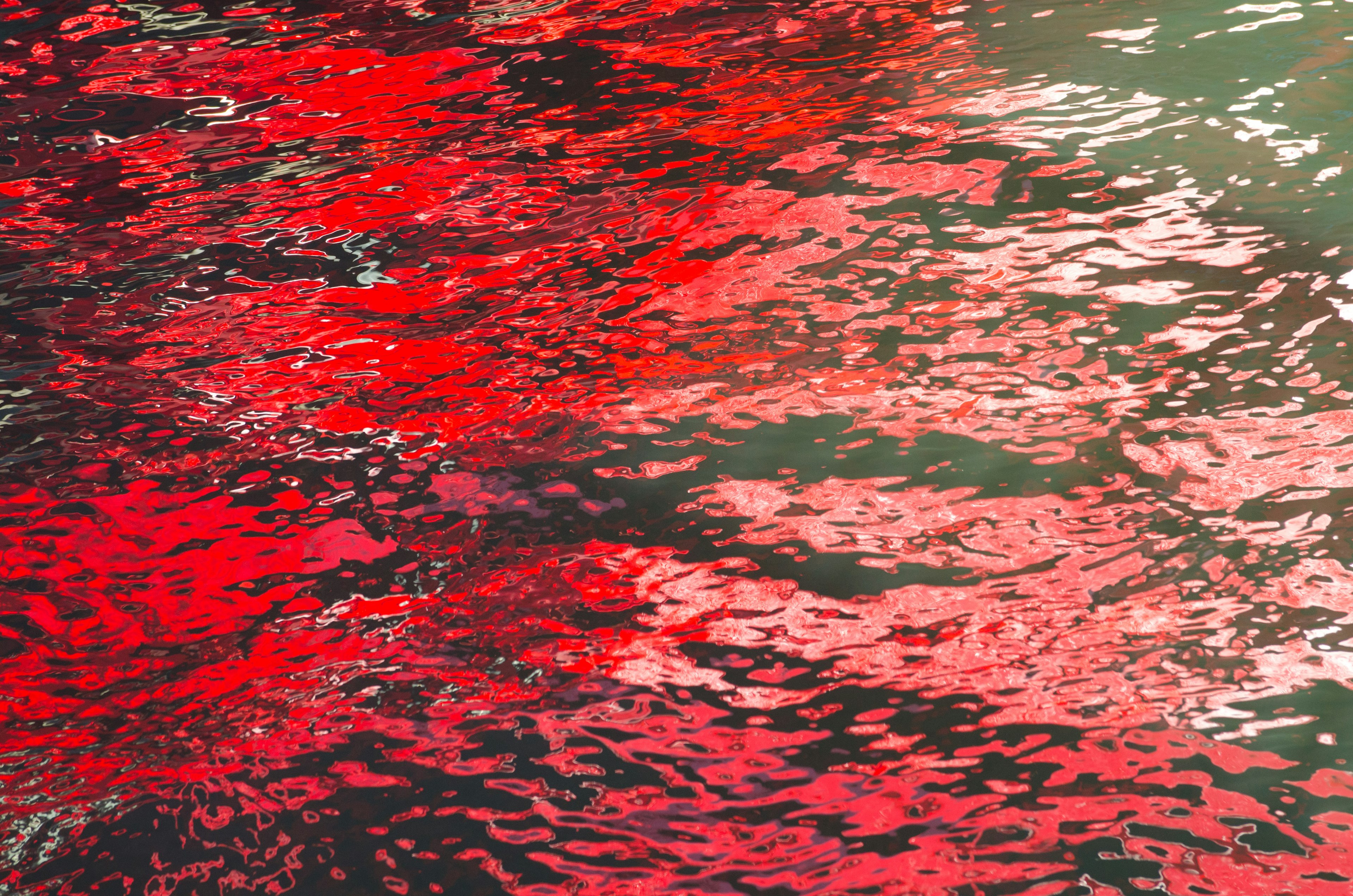 Beautiful patterns of red reflections and ripples on the water surface