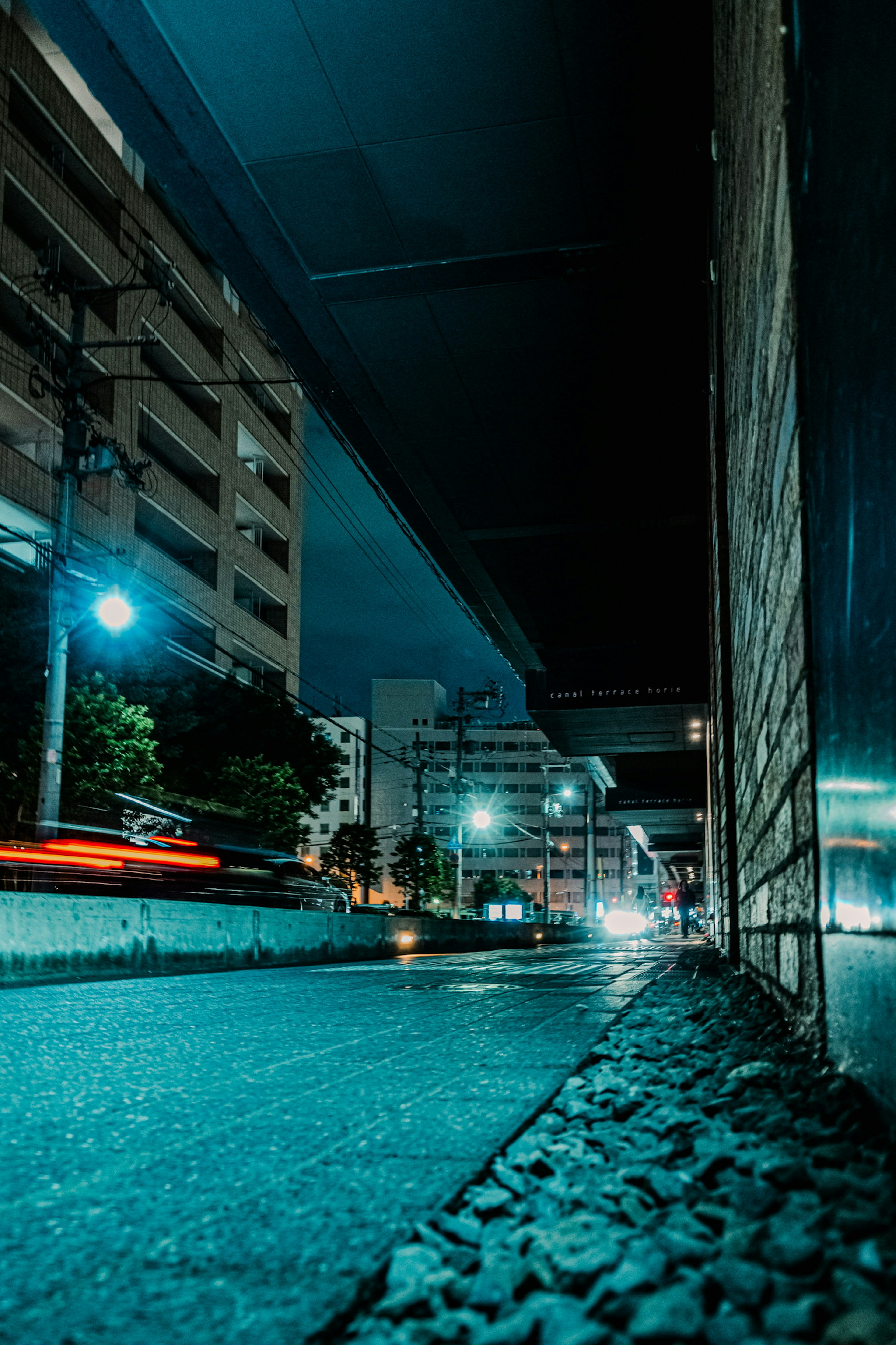 Low-angle view of a nighttime urban landscape with flowing car lights buildings and cobbled road