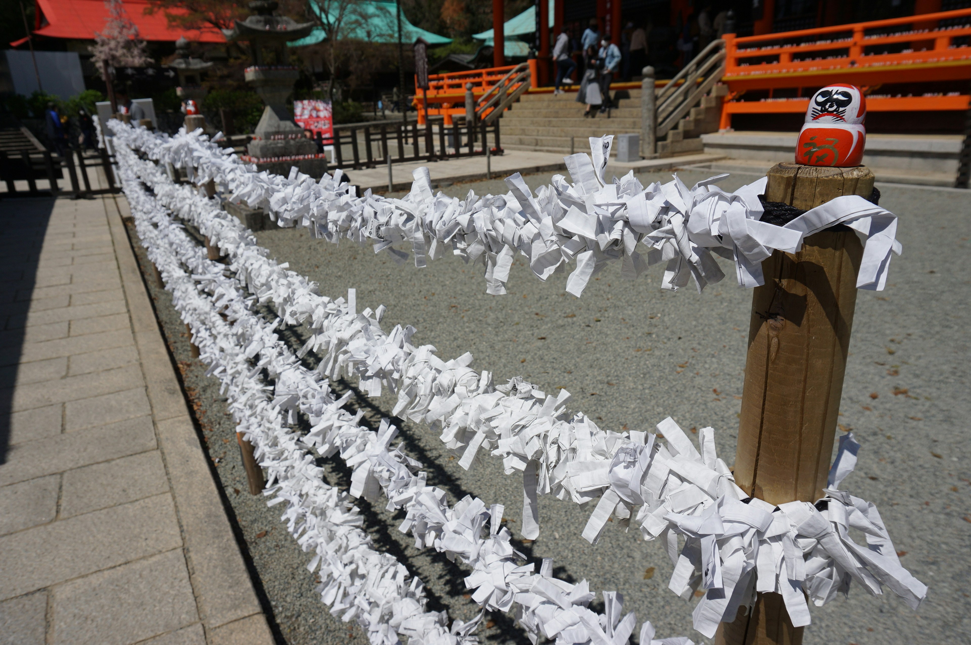 Pemandangan di kuil dengan omikuji putih tergantung di pagar kayu