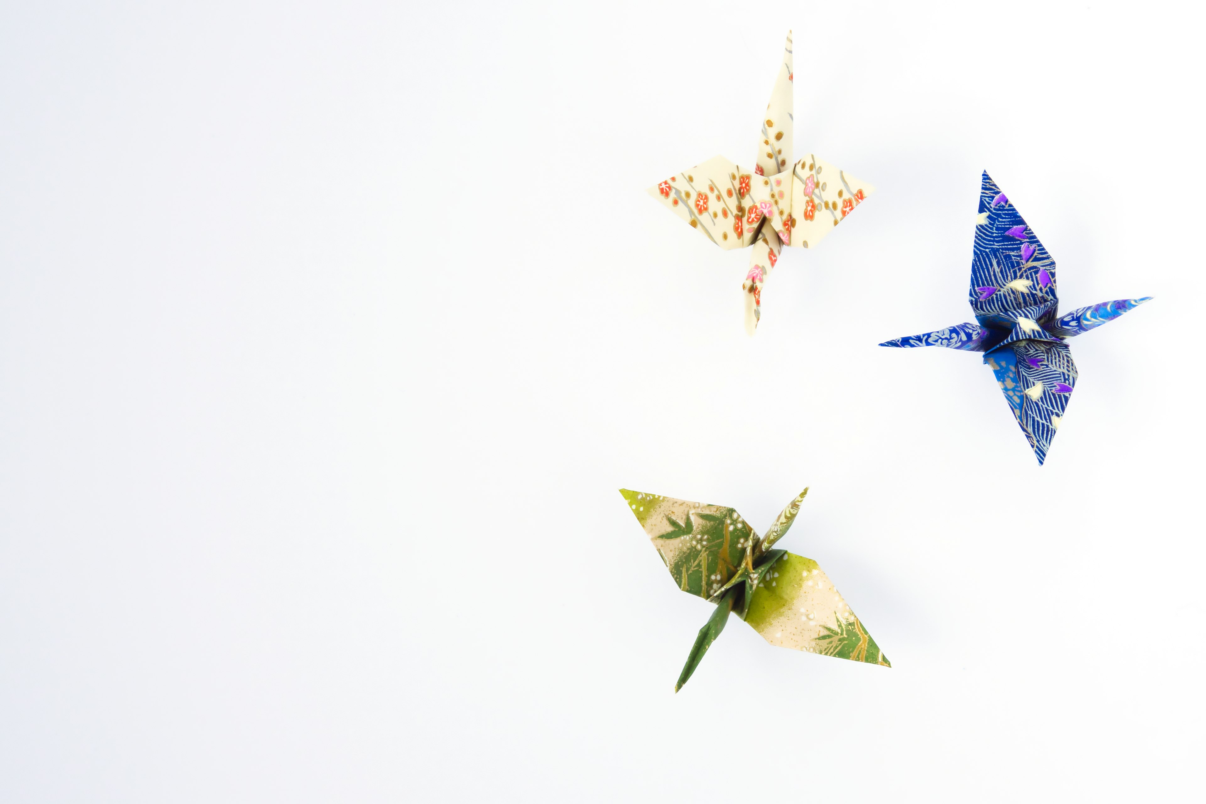 Colorful origami cranes floating against a white background