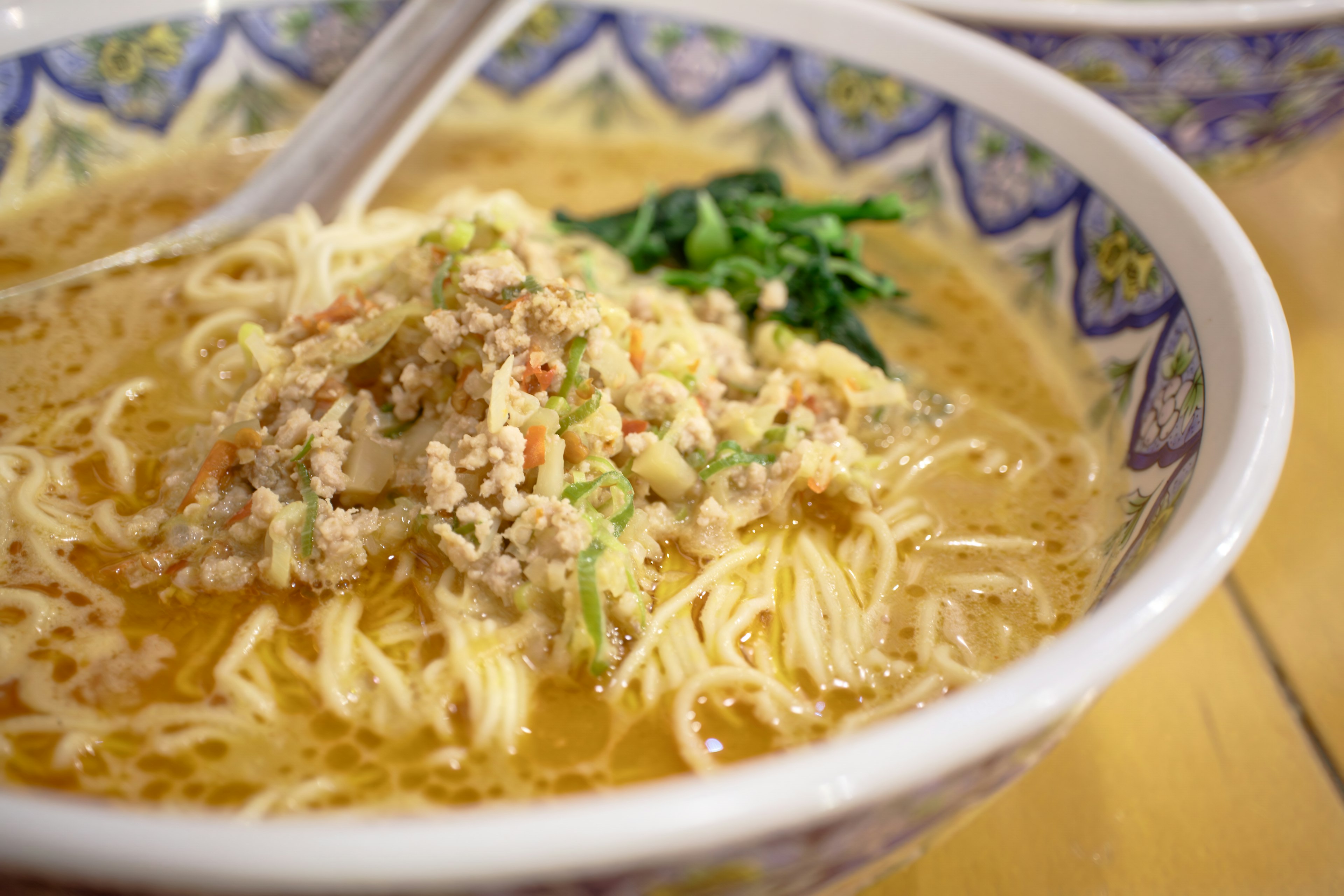 A bowl of delicious ramen with thin noodles topped with minced meat and vegetables