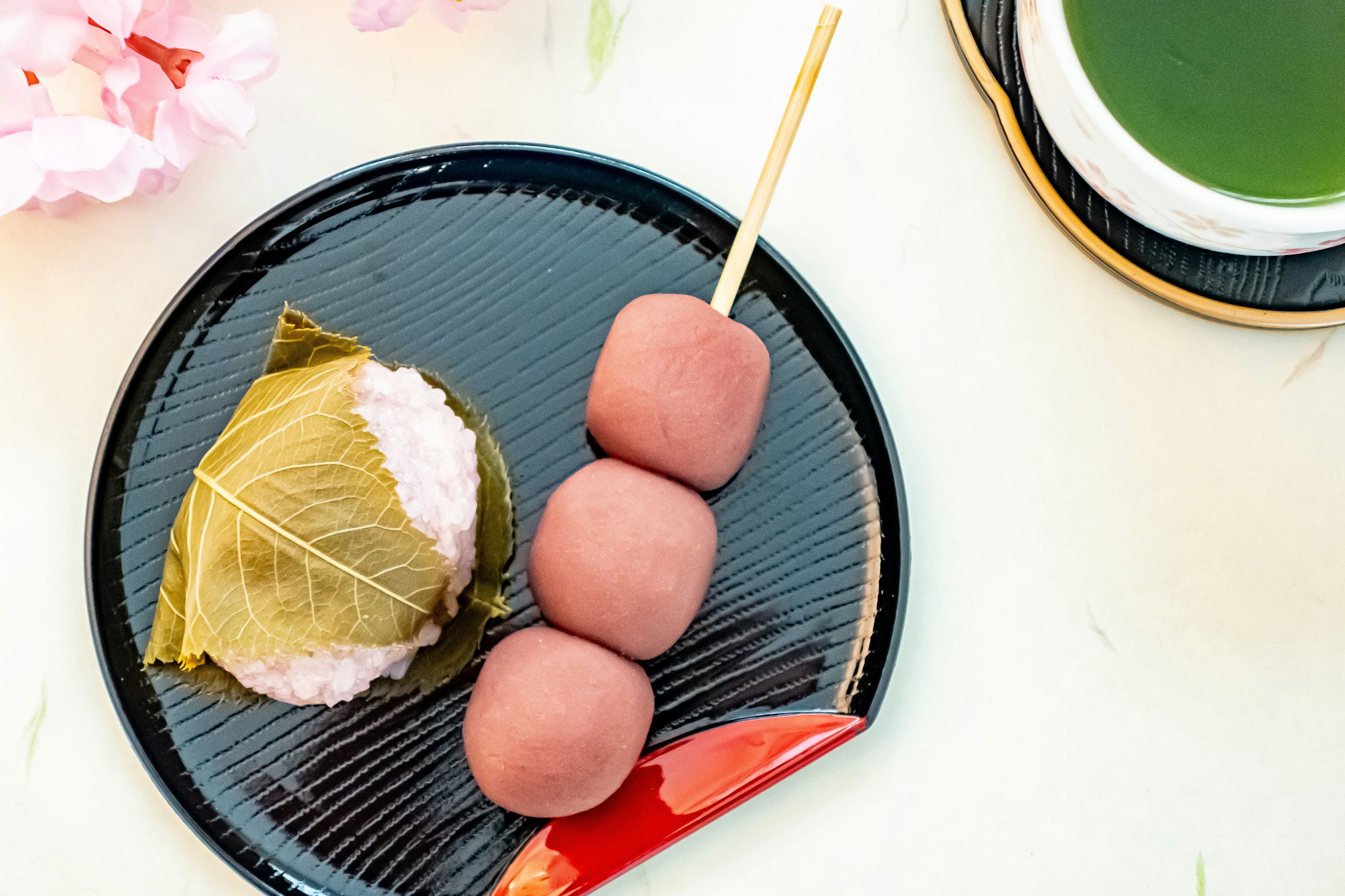 An arrangement of Japanese sweets next to cherry blossoms and green tea