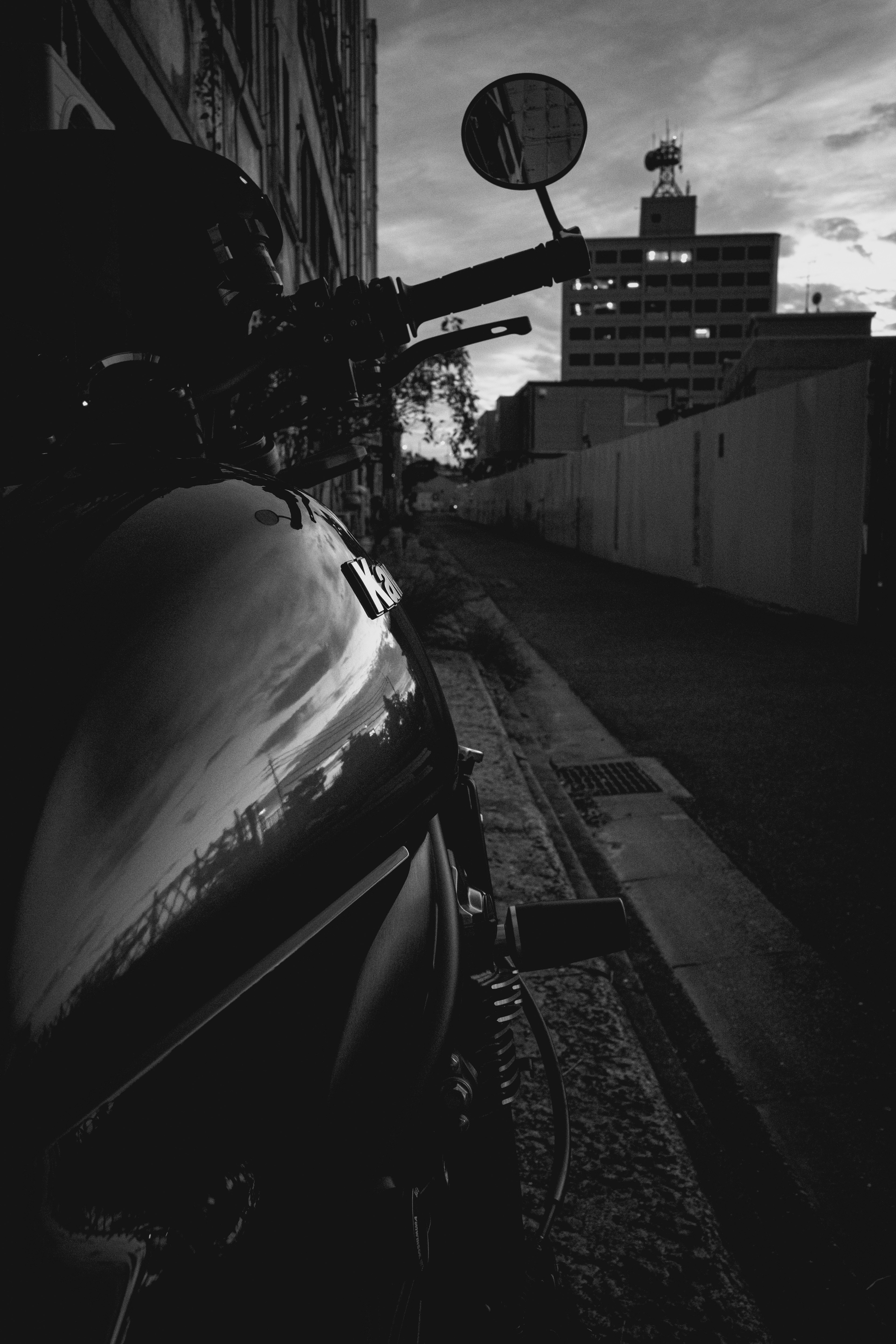 Motocicleta en blanco y negro estacionada en un callejón al atardecer