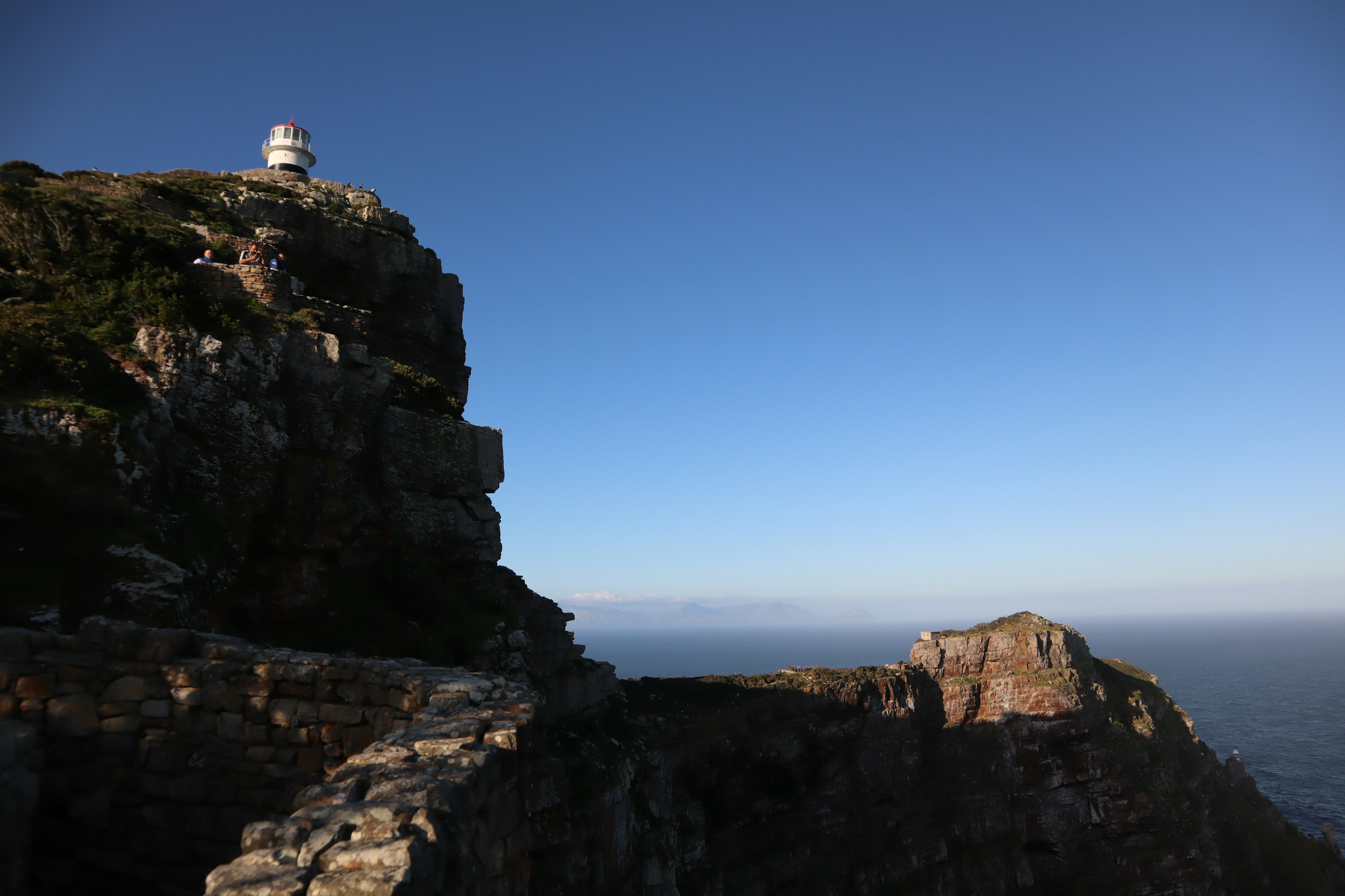 Vue pittoresque d'une montagne rocheuse avec un phare sous un ciel bleu clair