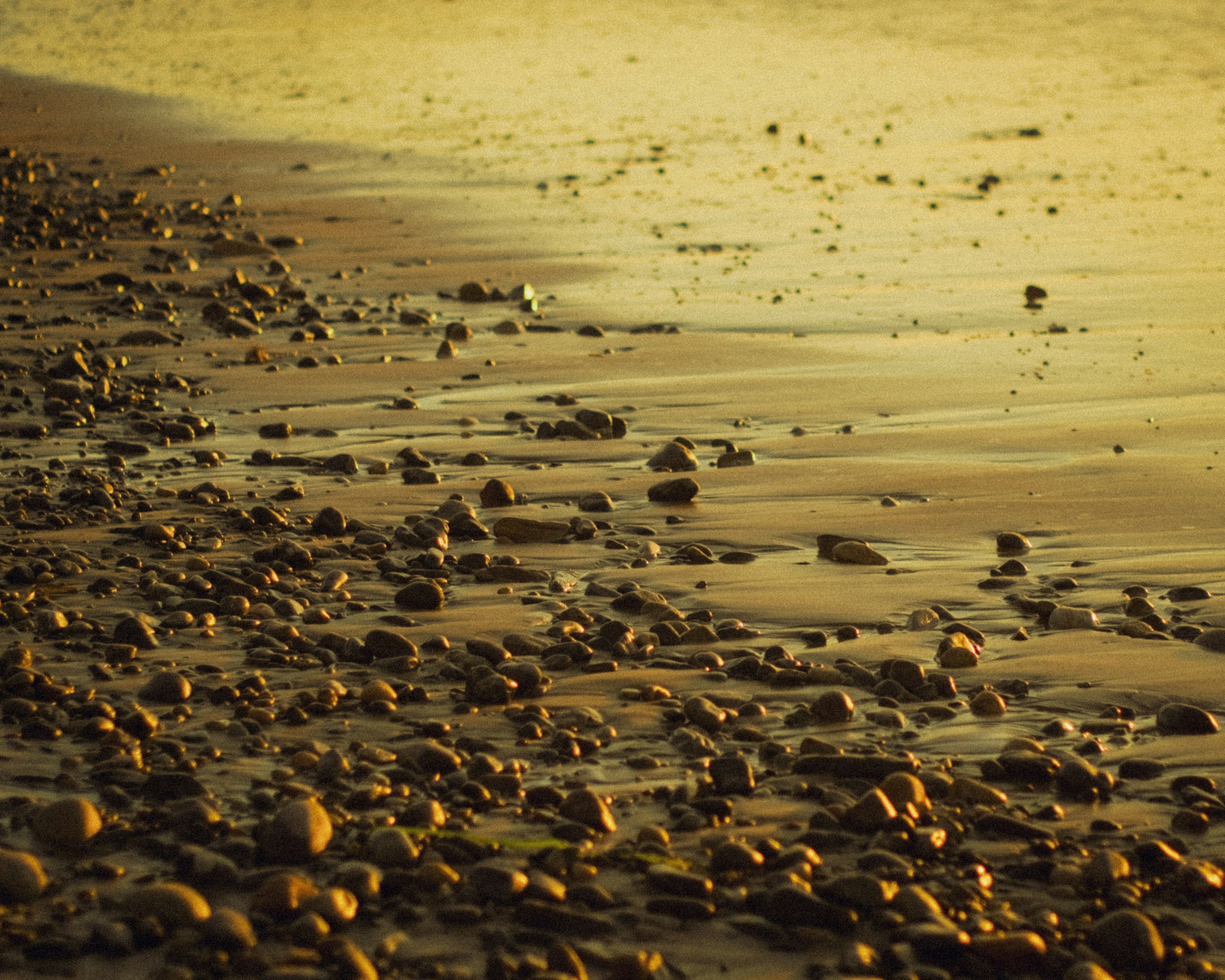 Pemandangan kerikil di pantai dengan ombak lembut