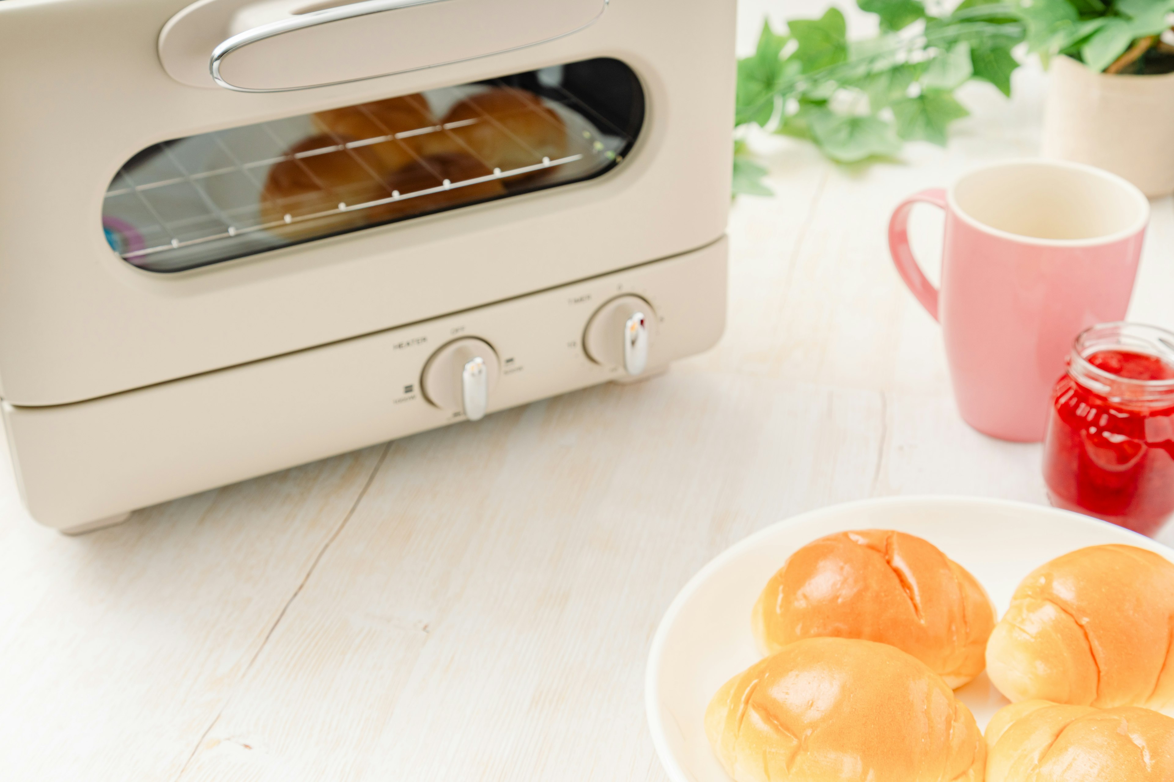 Frisch gebackene Brötchen vor einem Toaster mit einer Tasse Tee