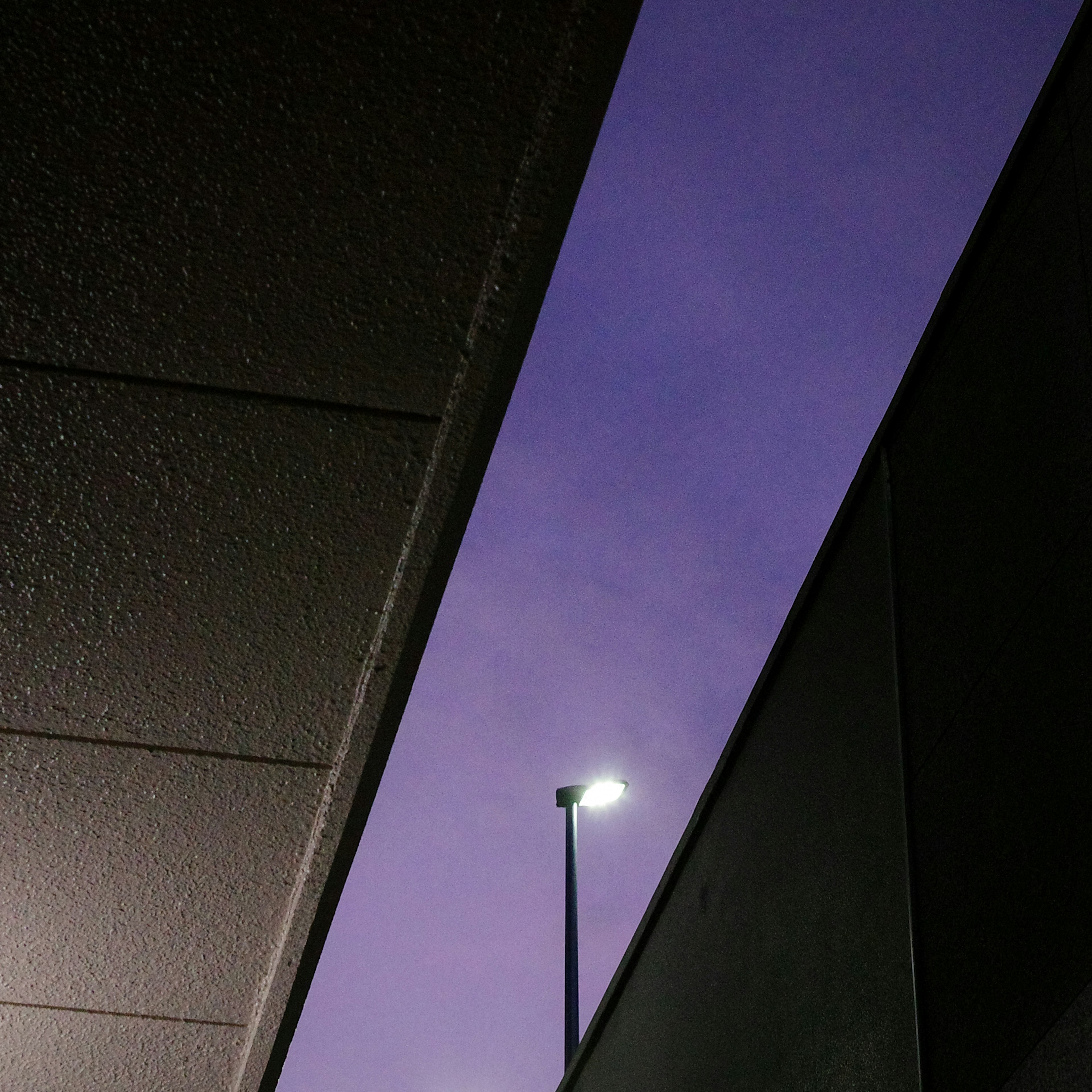 Vue d'un ciel violet avec un lampadaire visible entre des bâtiments