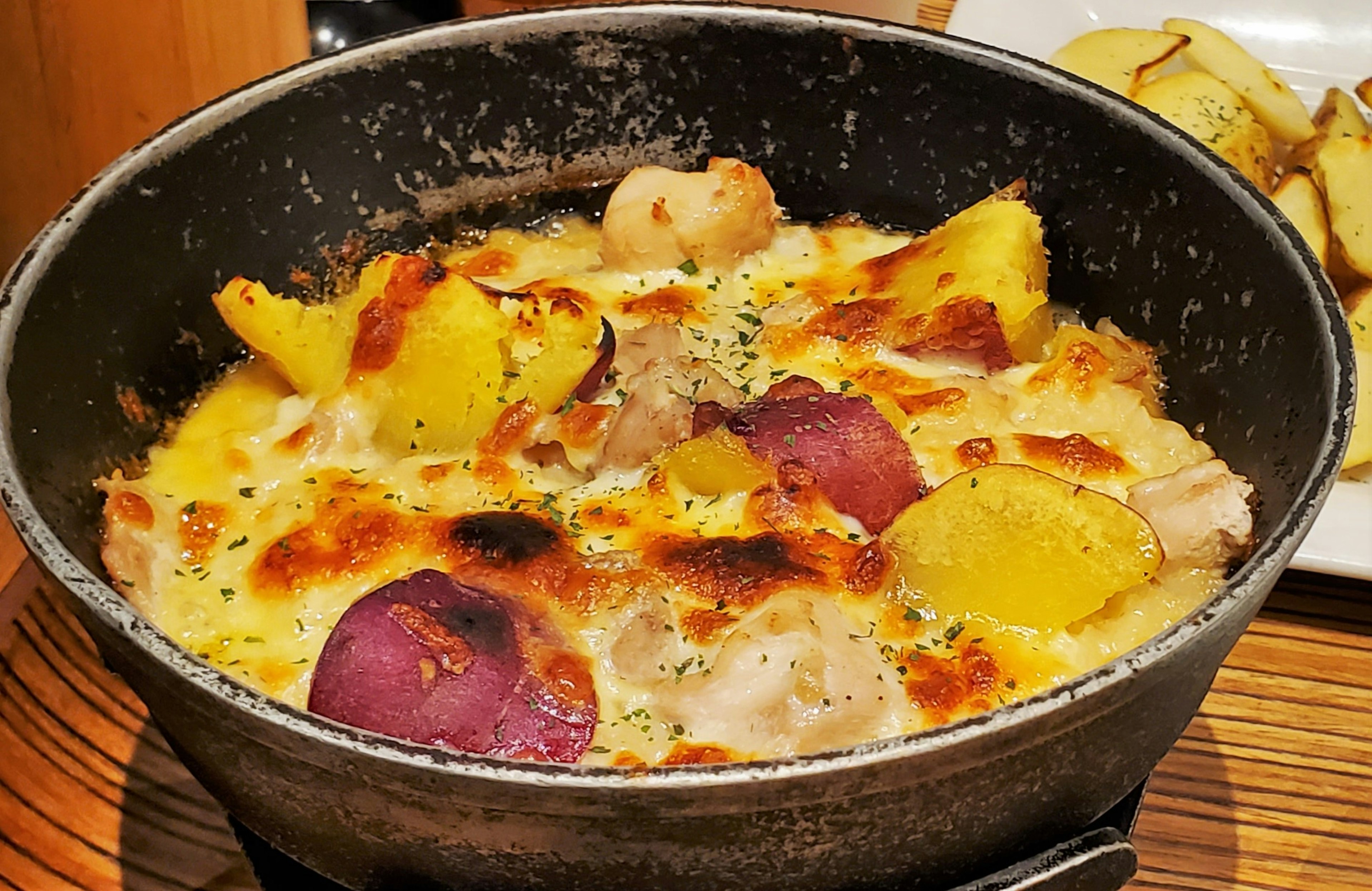 Cheesy vegetable gratin in a black pot with a golden crust