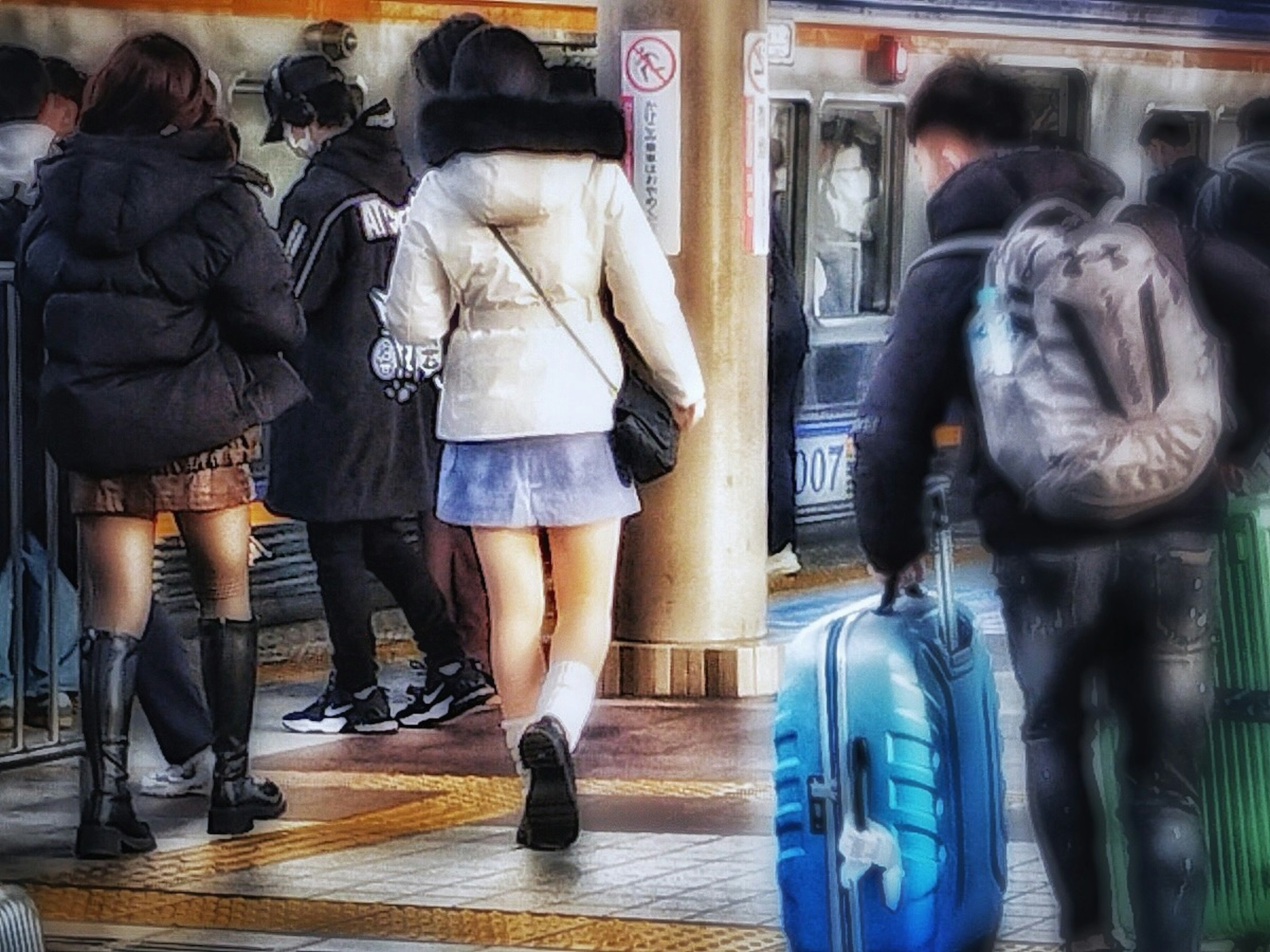 駅で歩く人々と青いスーツケースを持つ女性の後姿