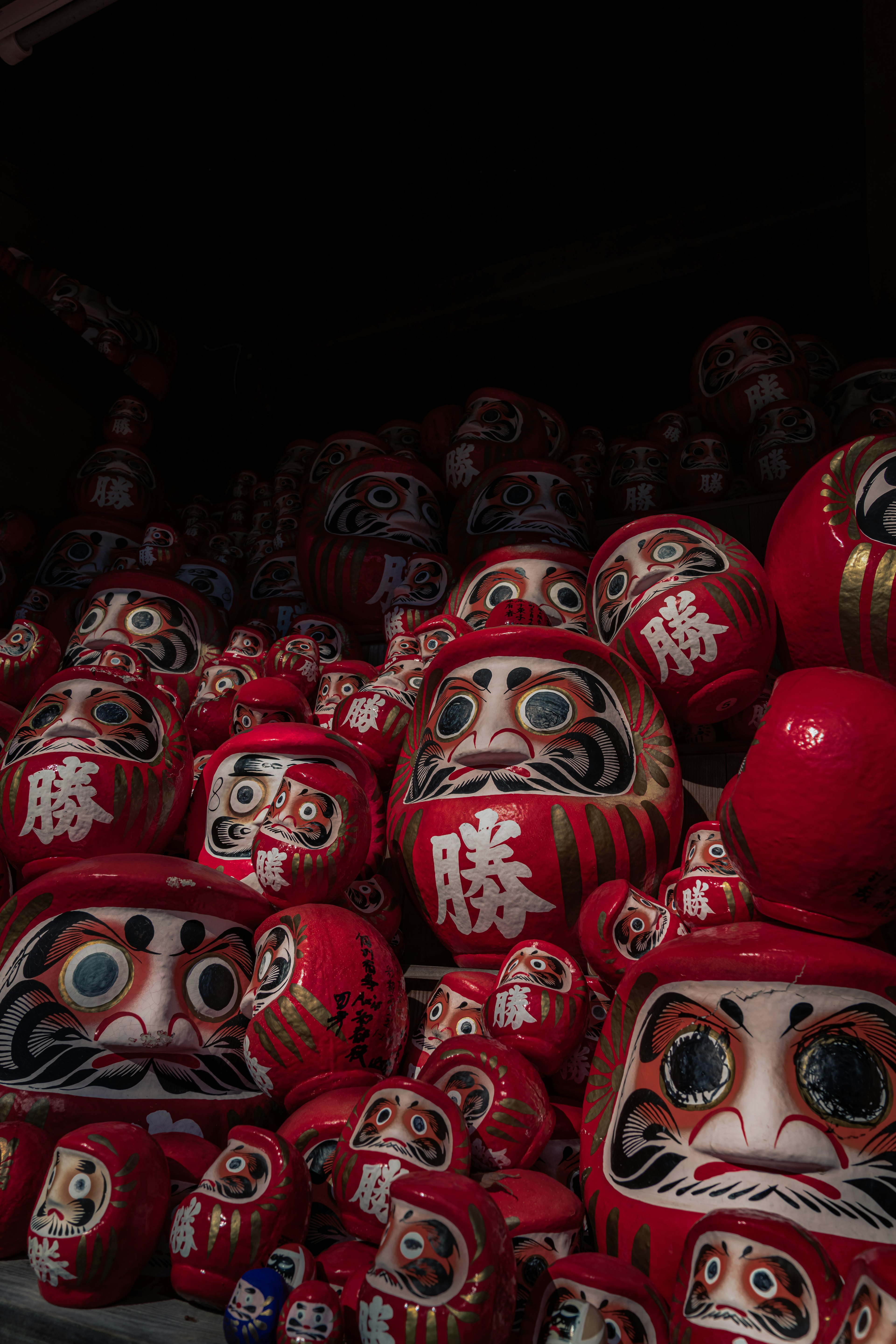 A collection of stacked red daruma dolls with distinct facial features