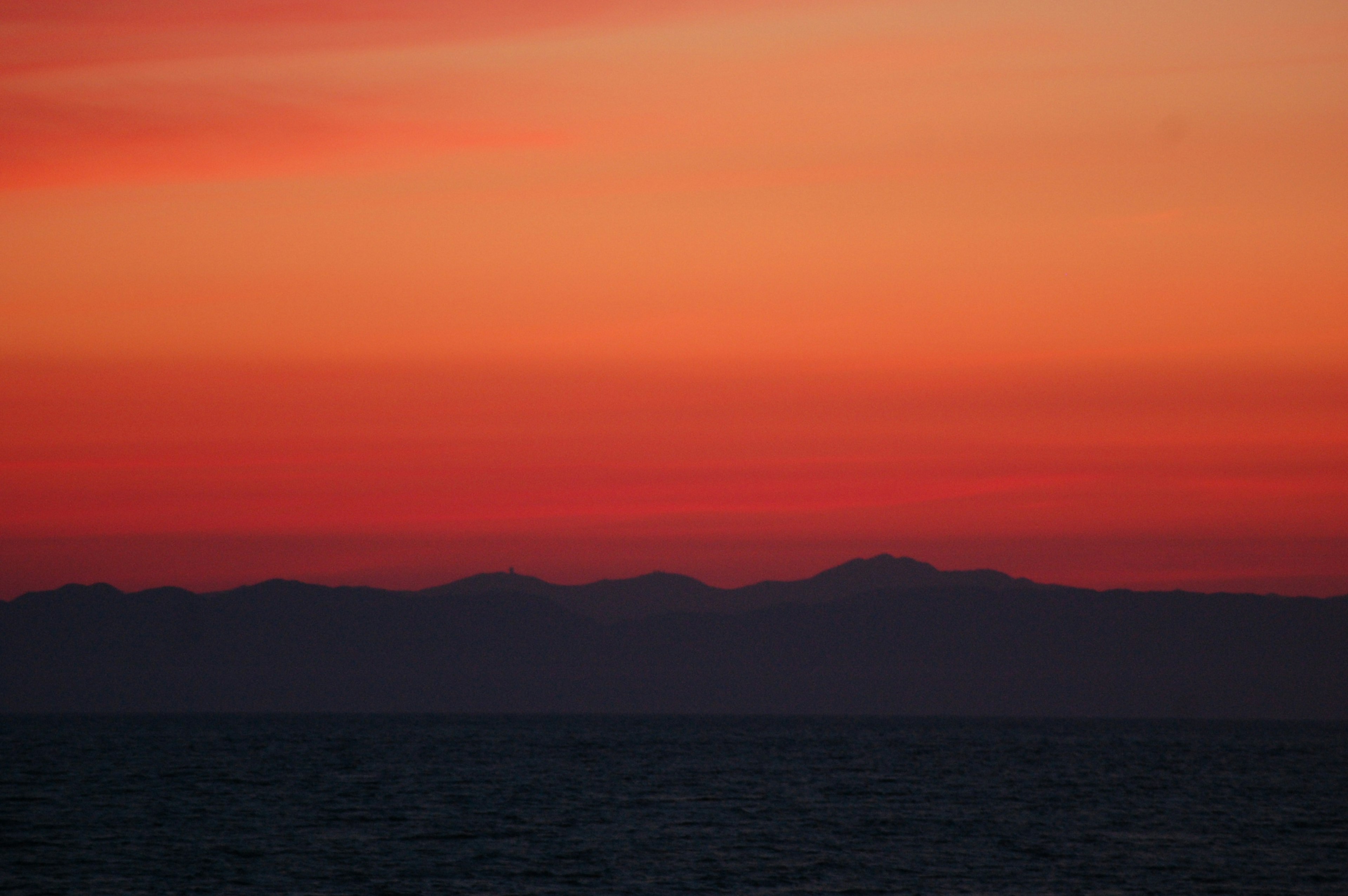 Magnifico cielo al tramonto sopra l'oceano con montagne in silhouette