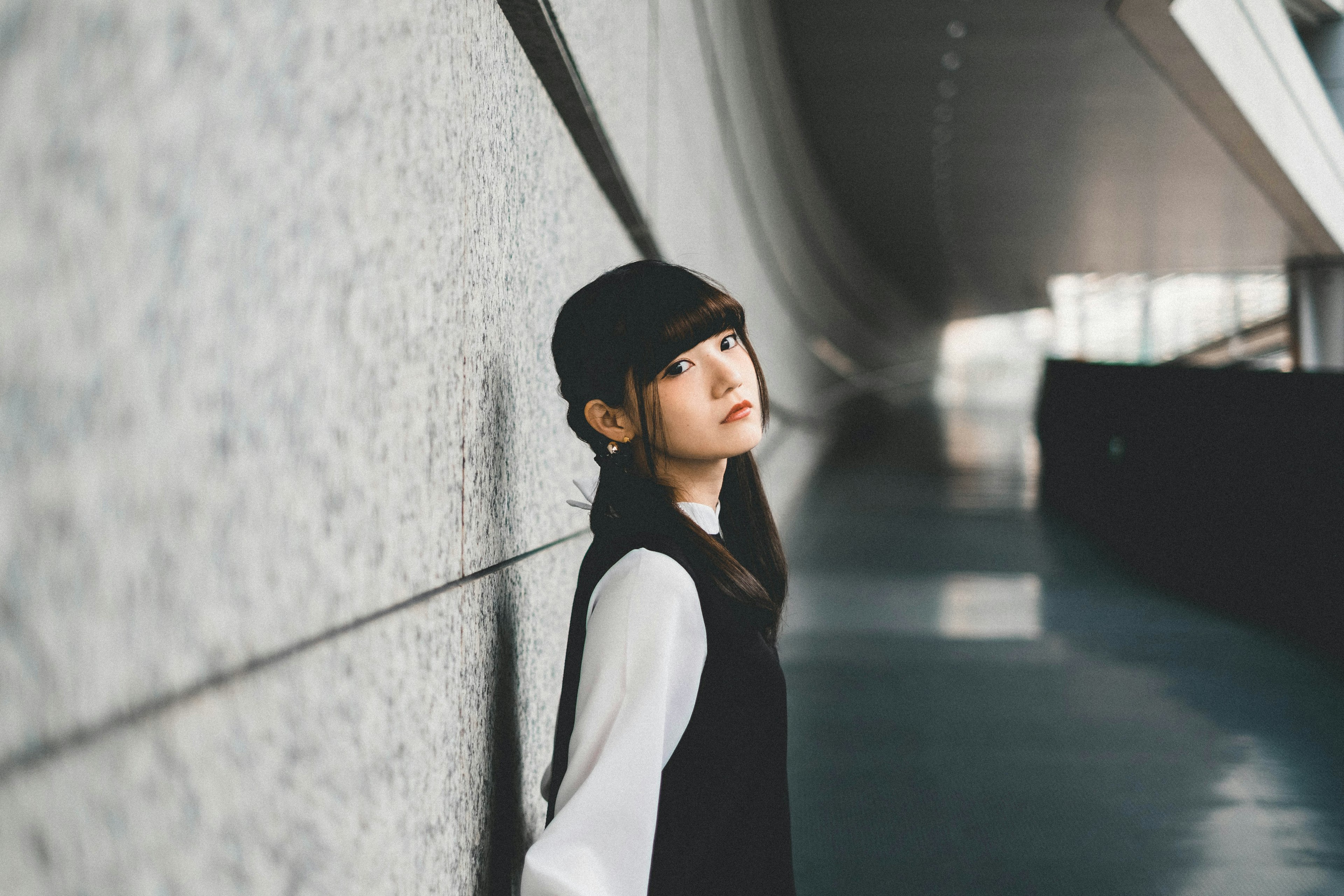 Mujer apoyada en una pared Fondo arquitectónico moderno Ropa simple y elegante