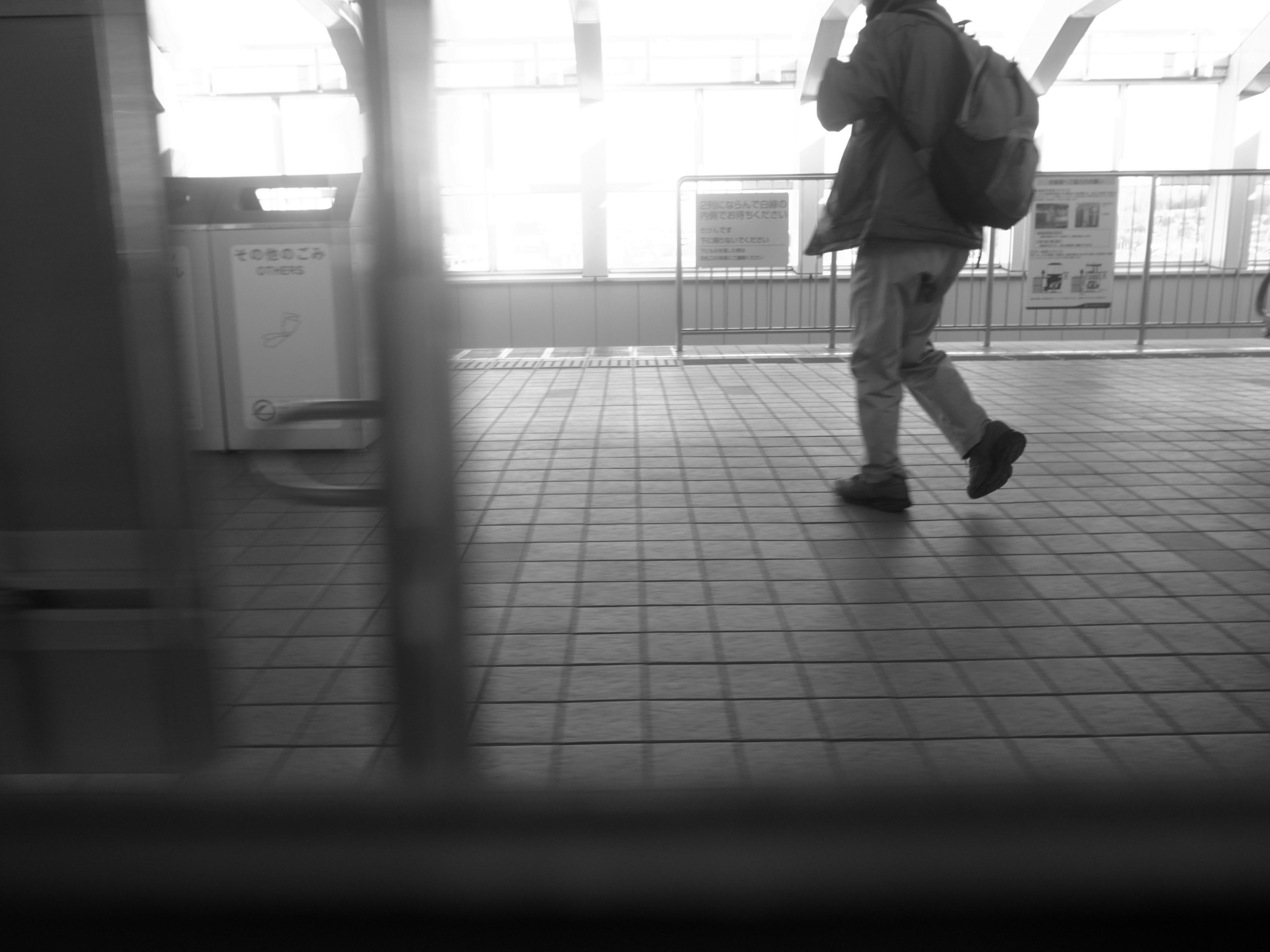 Black and white photo of a person walking on a train platform