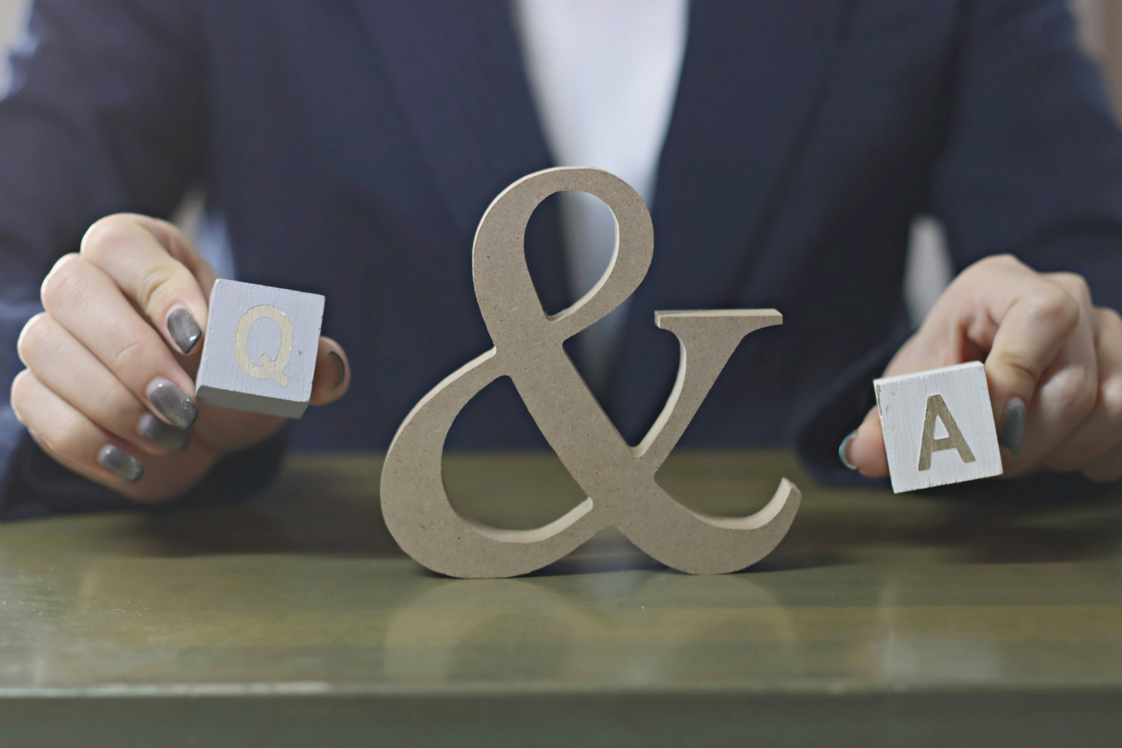 Hands in business suit holding an ampersand and Q A blocks