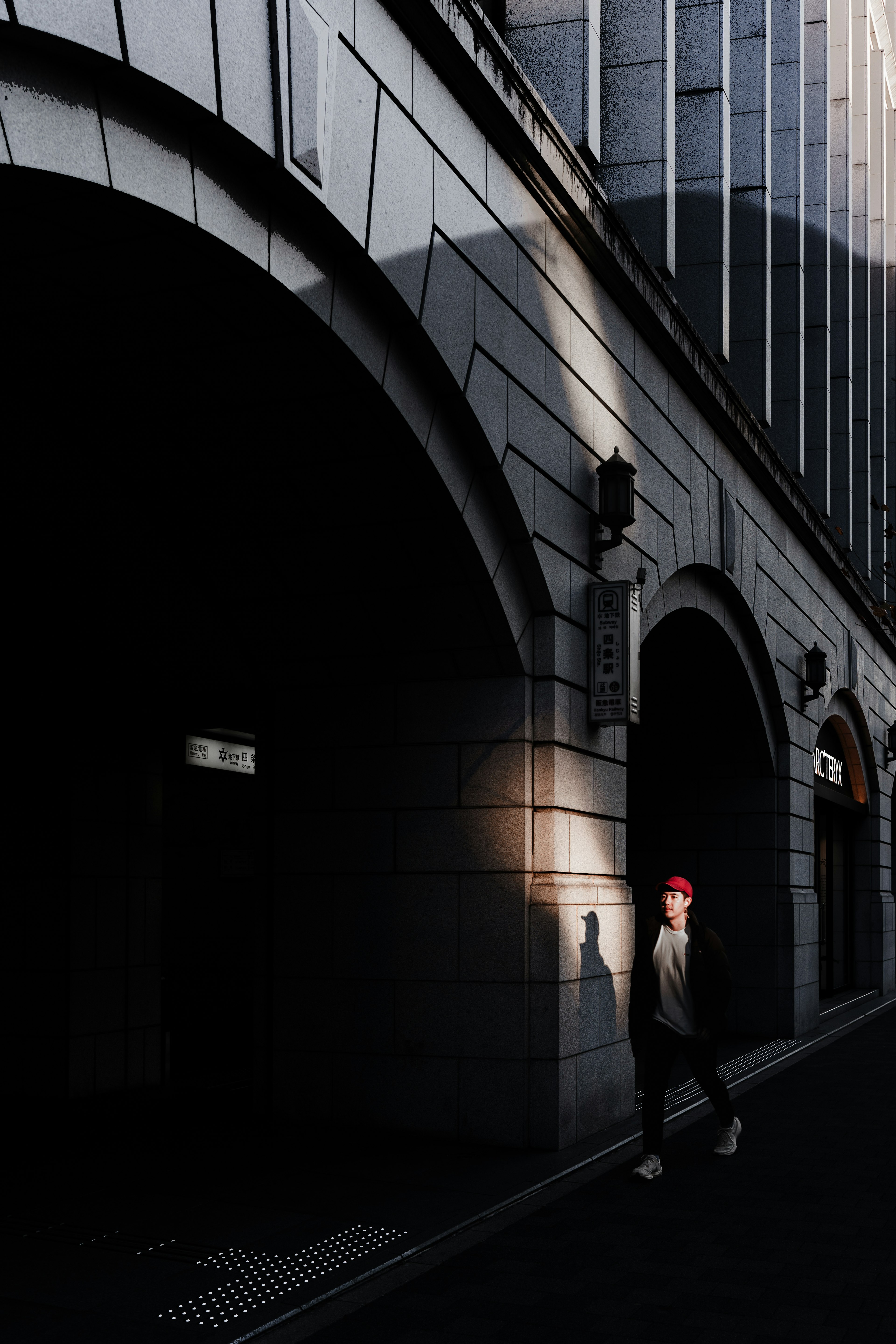 Una persona con un cappello rosso che cammina sotto un arco scuro