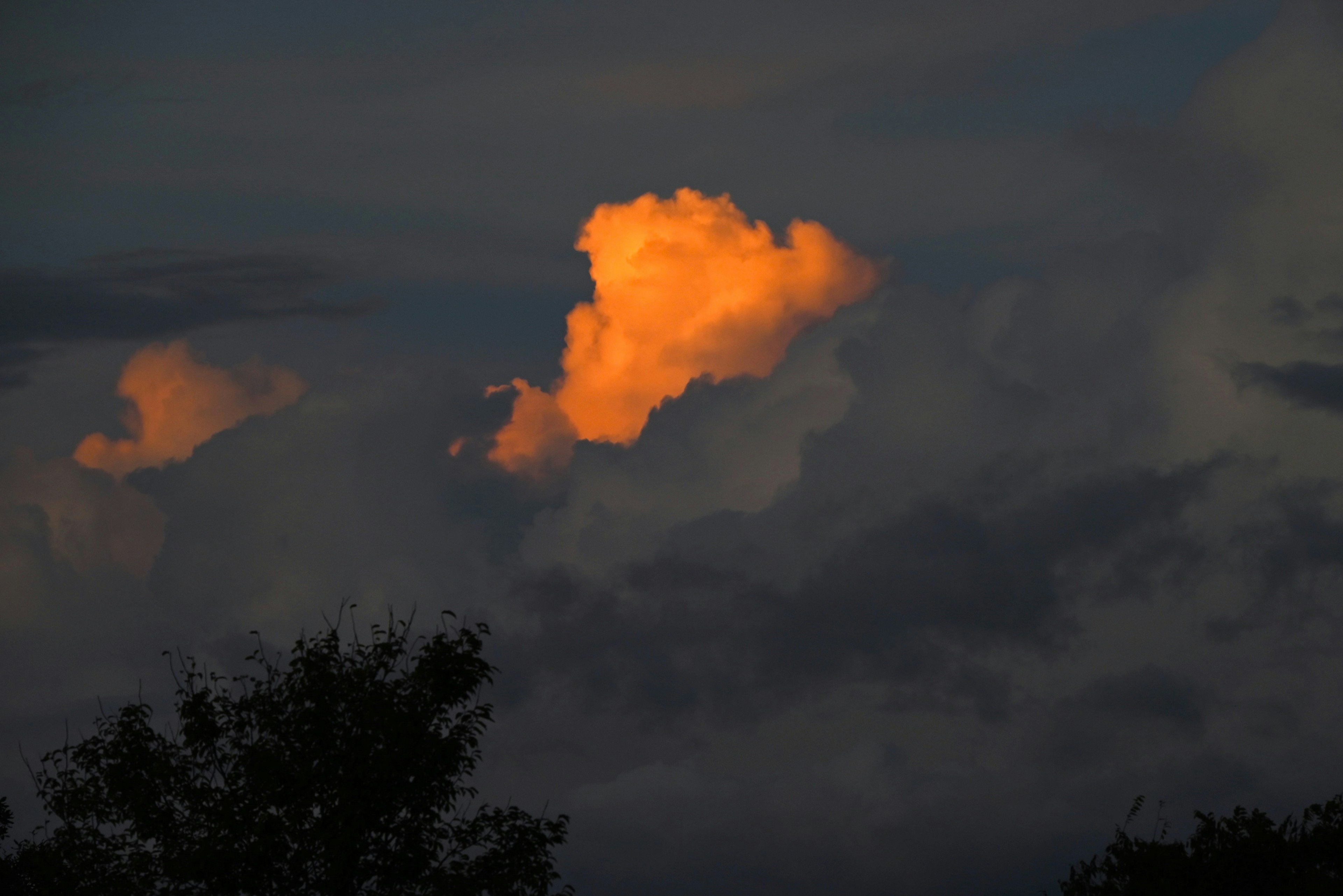 Kontrast einer vom Sonnenuntergang beleuchteten Wolke vor einem dunklen Himmel