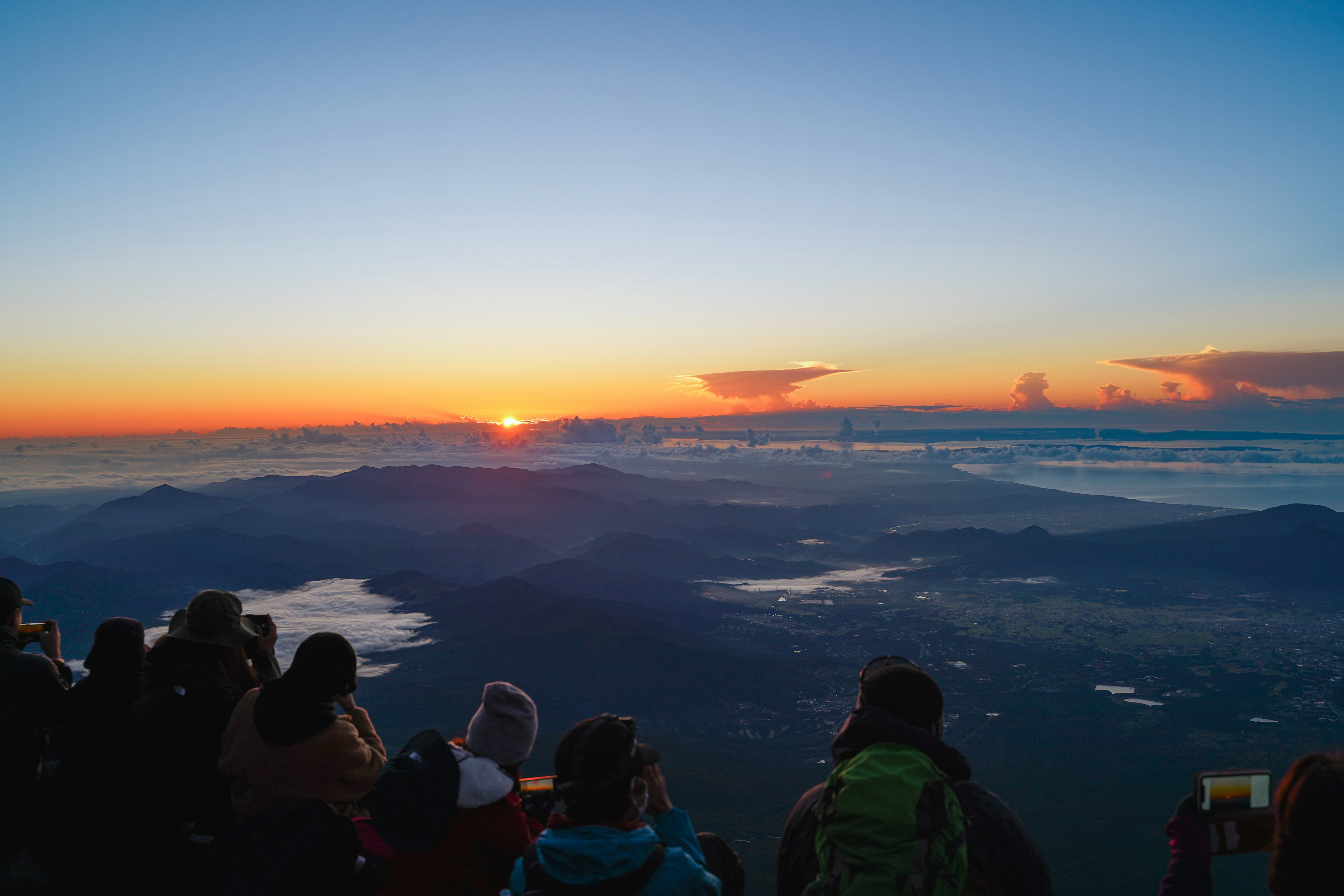 Pemandangan matahari terbit yang menakjubkan dari puncak gunung dengan siluet wisatawan