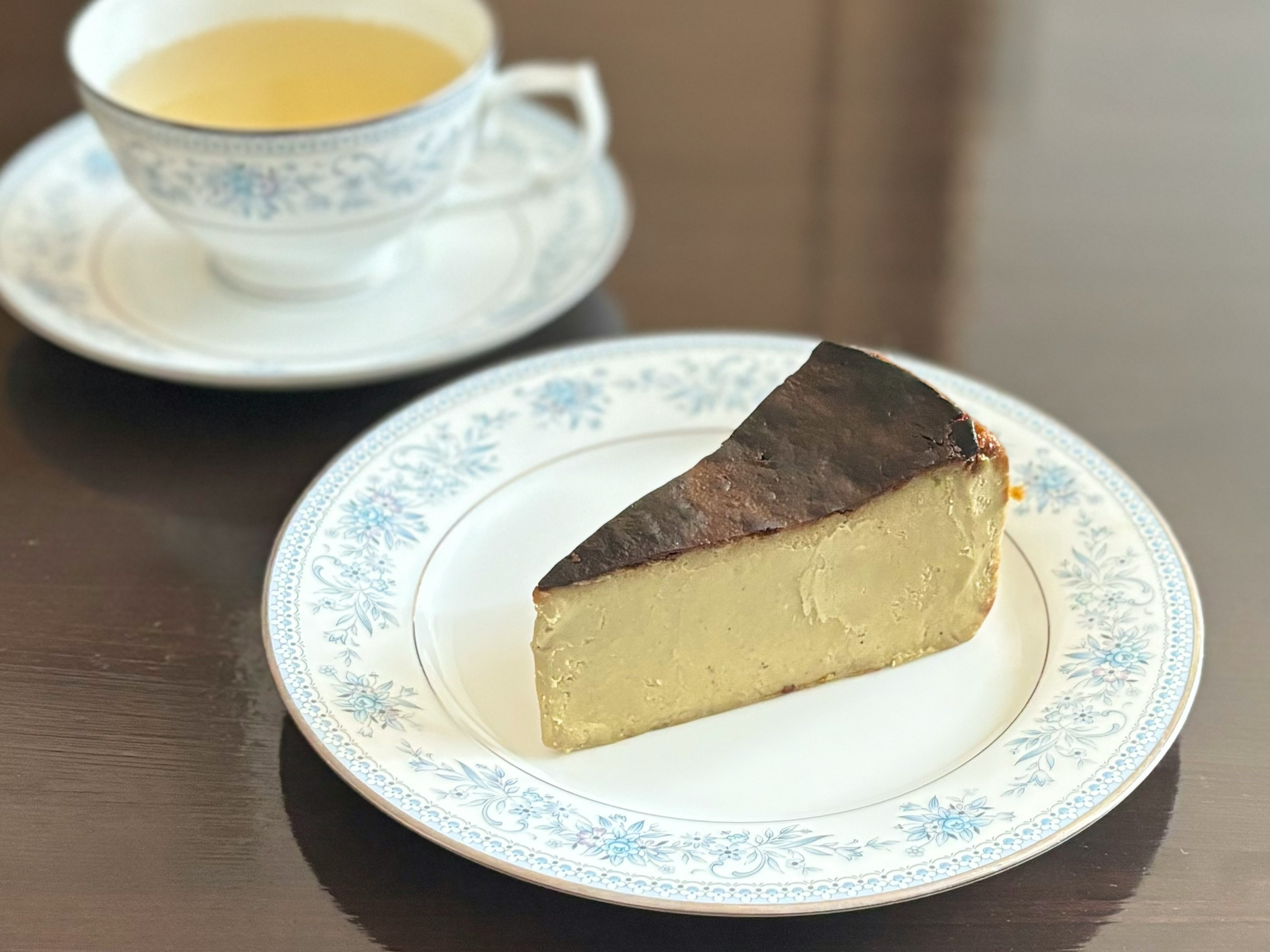 美しいデザインの皿に載ったチーズケーキとティーカップのセット