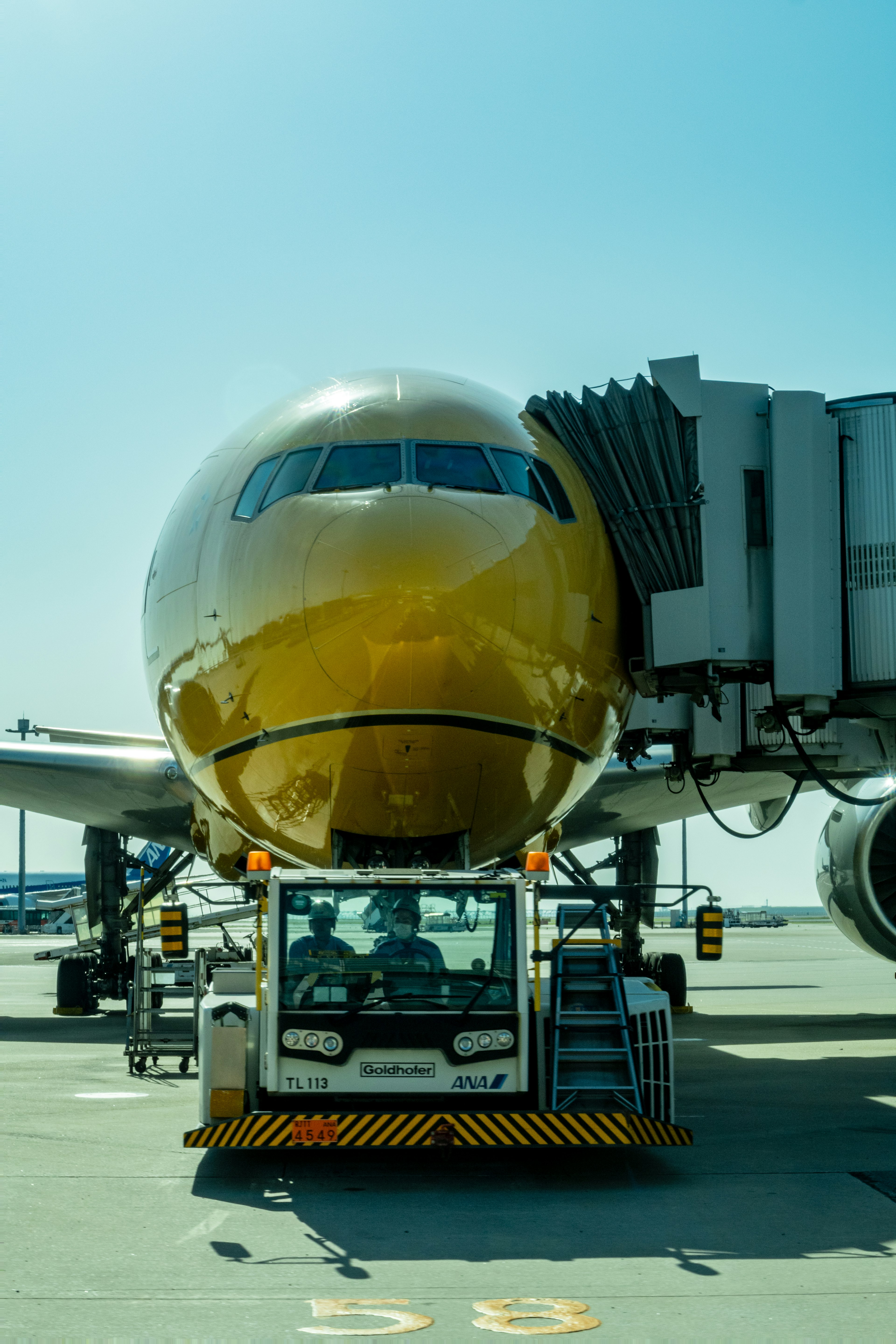 Avión dorado conectado a la puerta en el aeropuerto con un tractor de remolque