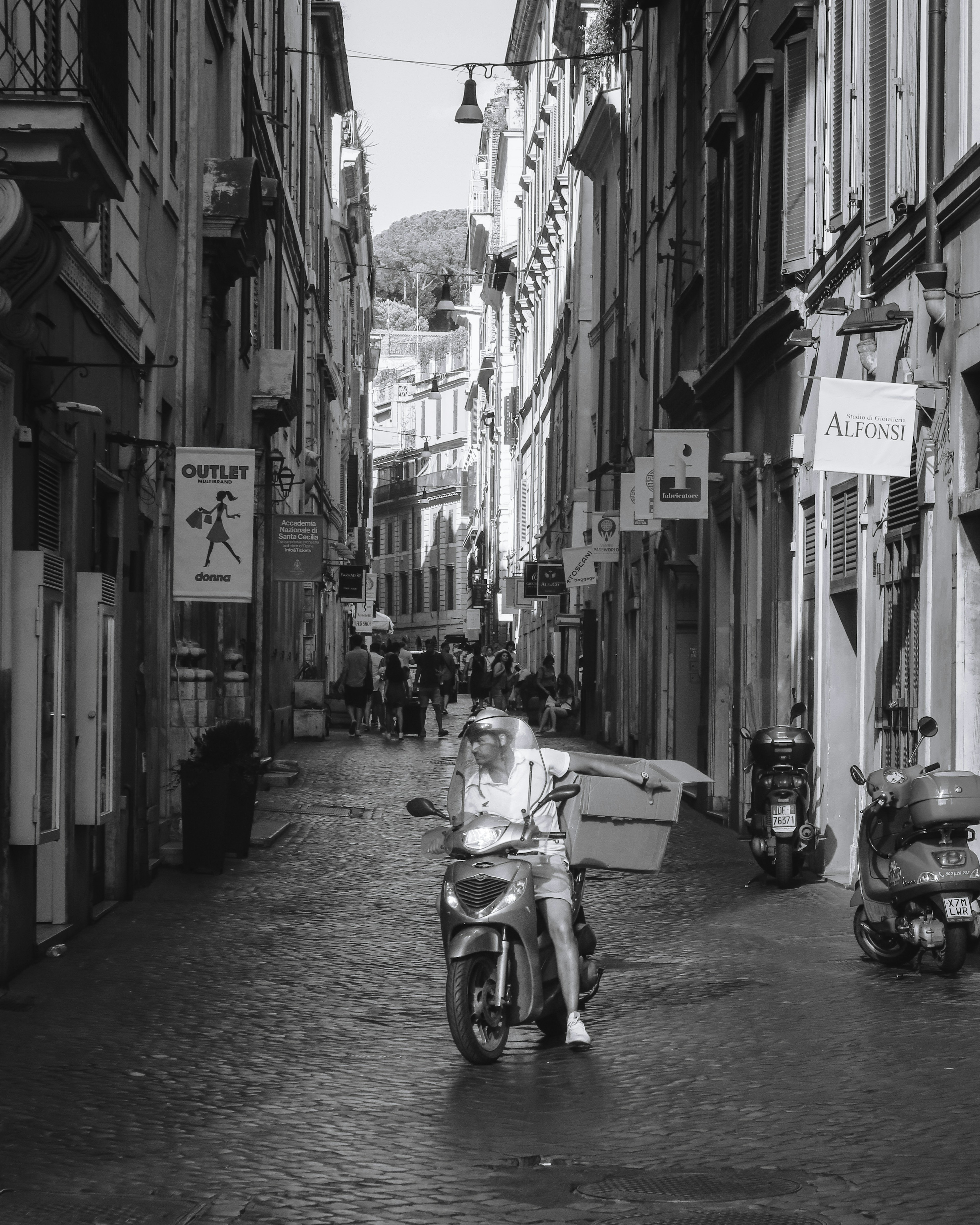 Repartidor en motocicleta en una calle estrecha con edificios