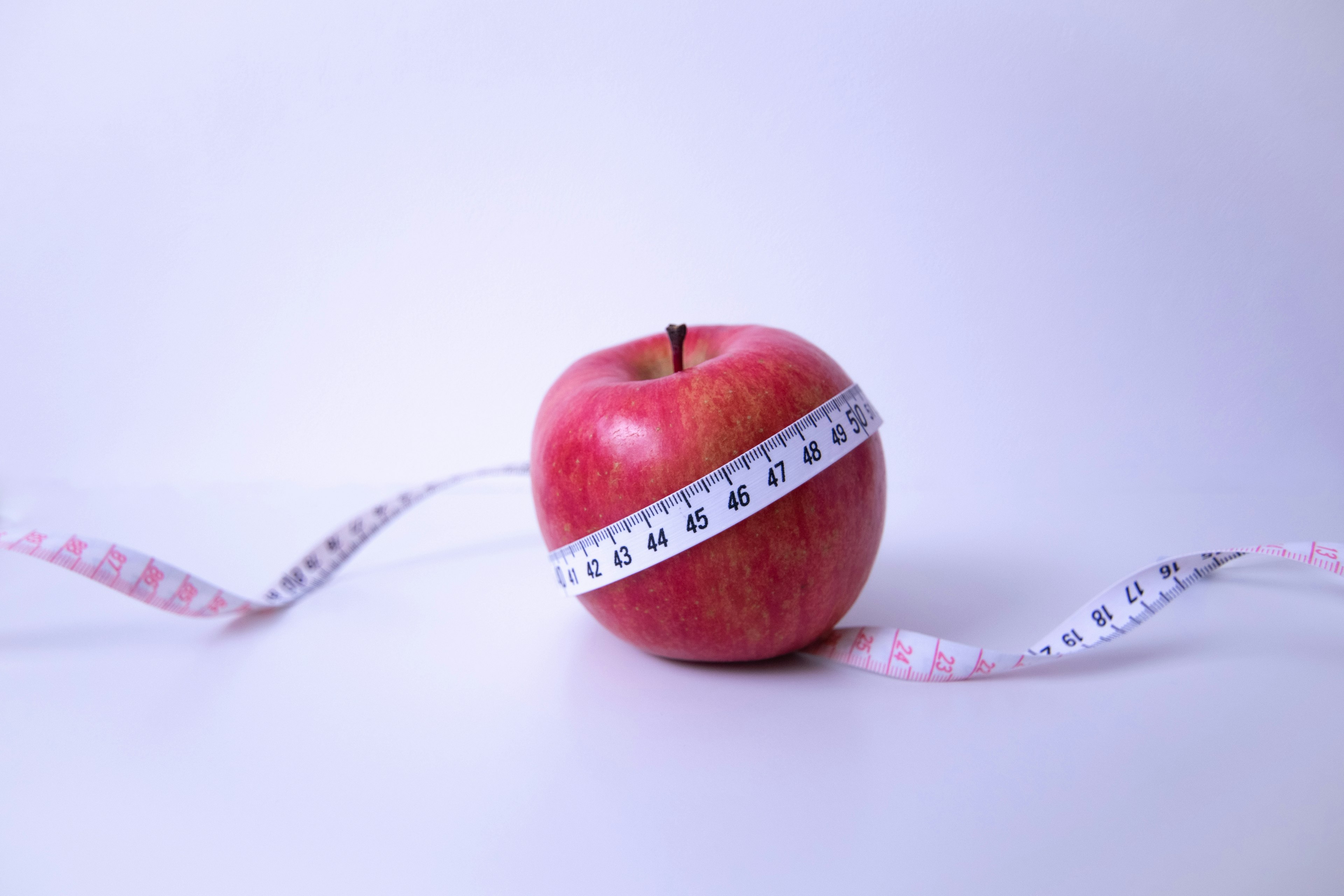 Une pomme rouge entourée d'un ruban à mesurer