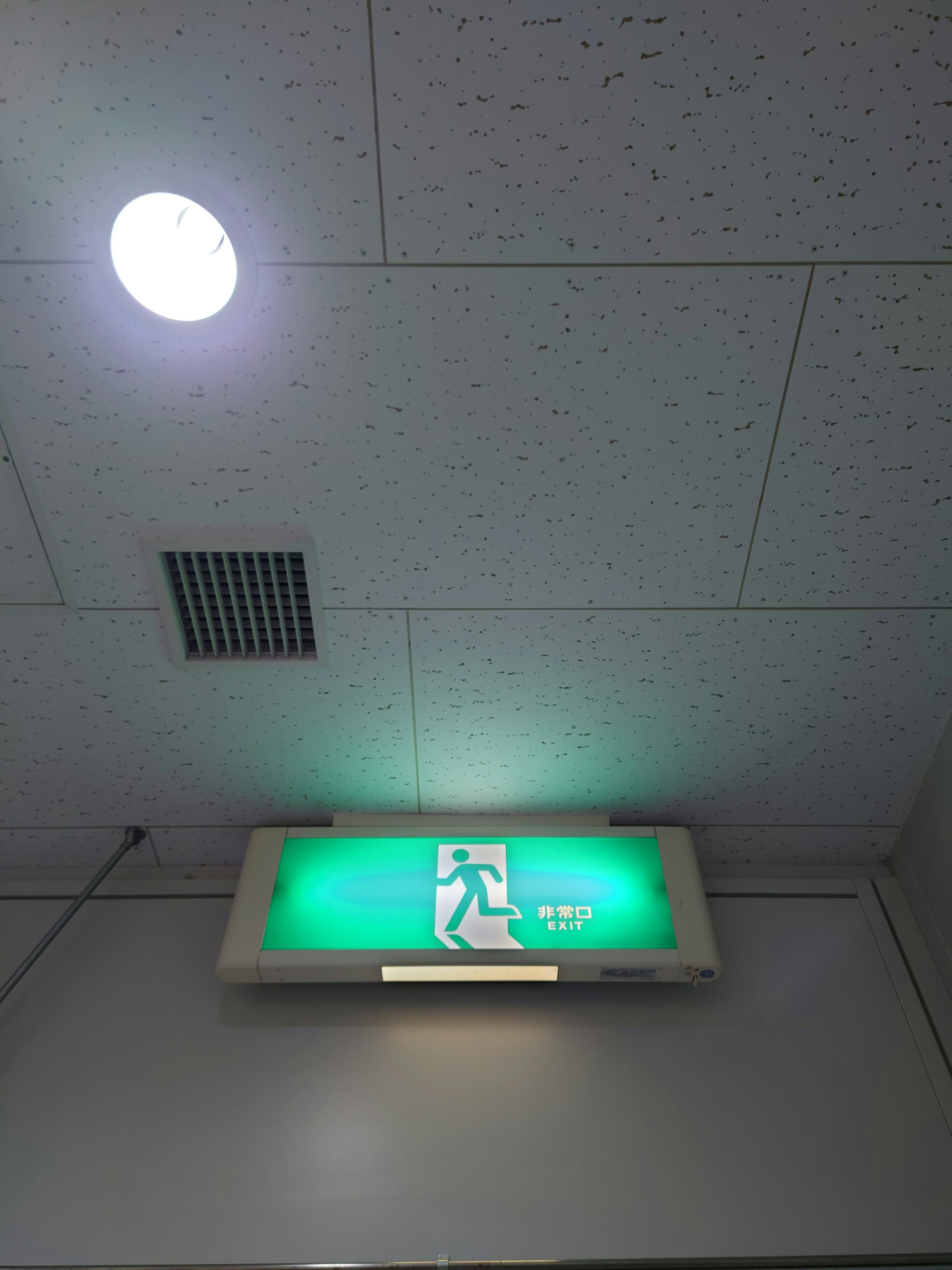 Vue intérieure avec un panneau de sortie de secours vert et une lumière de plafond