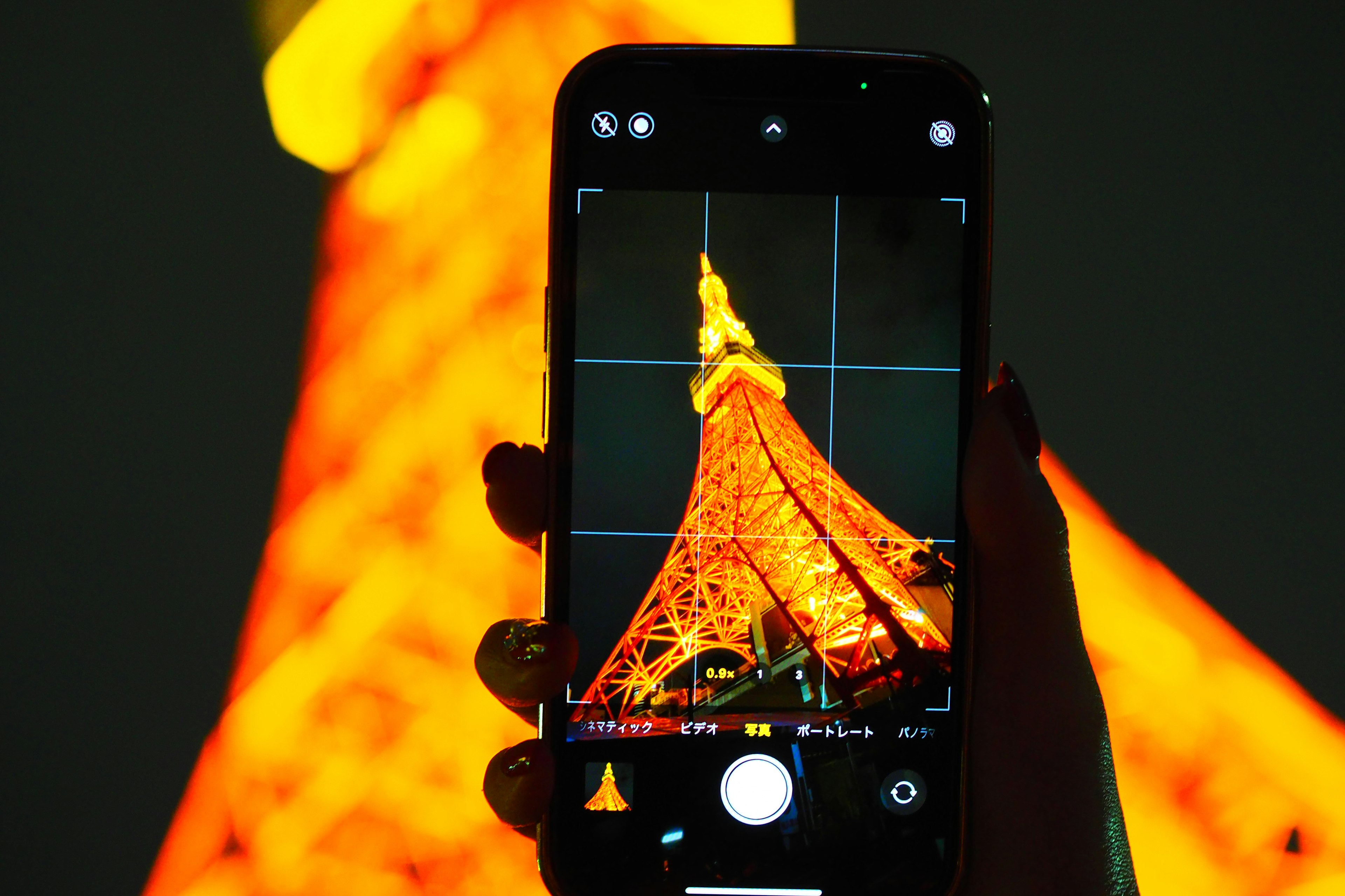 Une main tenant un smartphone capturant la Tour de Tokyo