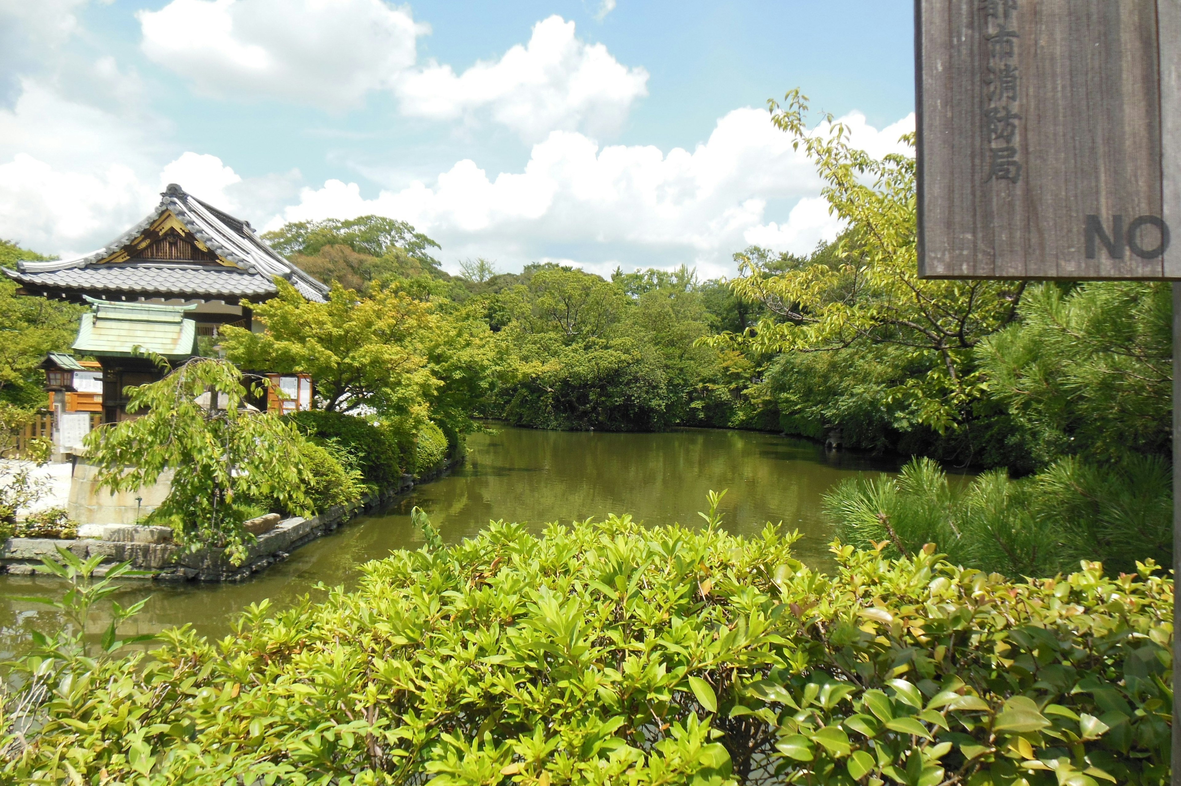 傳統日本建築的風景，周圍環繞著池塘和郁郁蔥蔥的綠樹