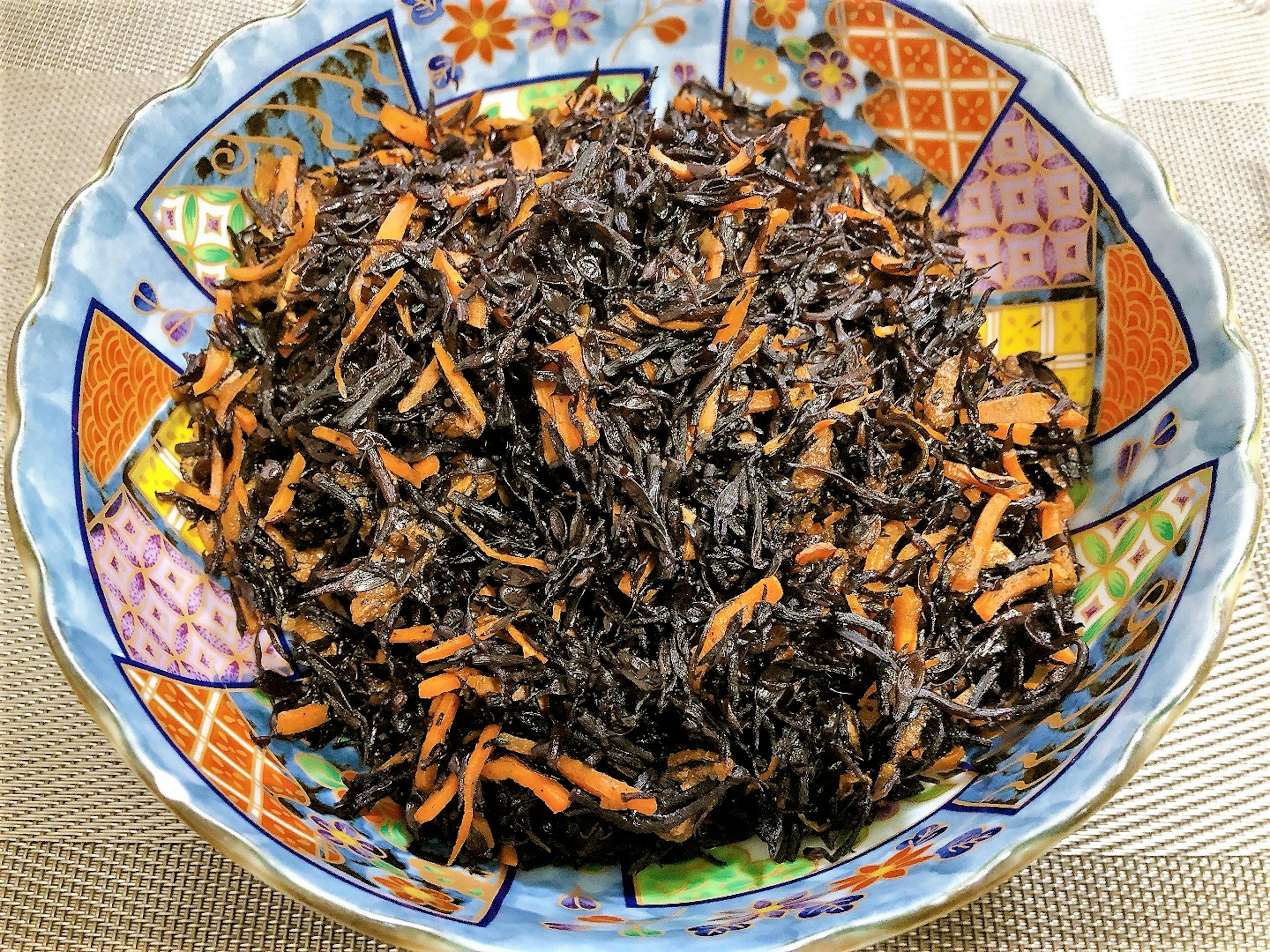 Bowl of black seaweed mixed with shredded carrots