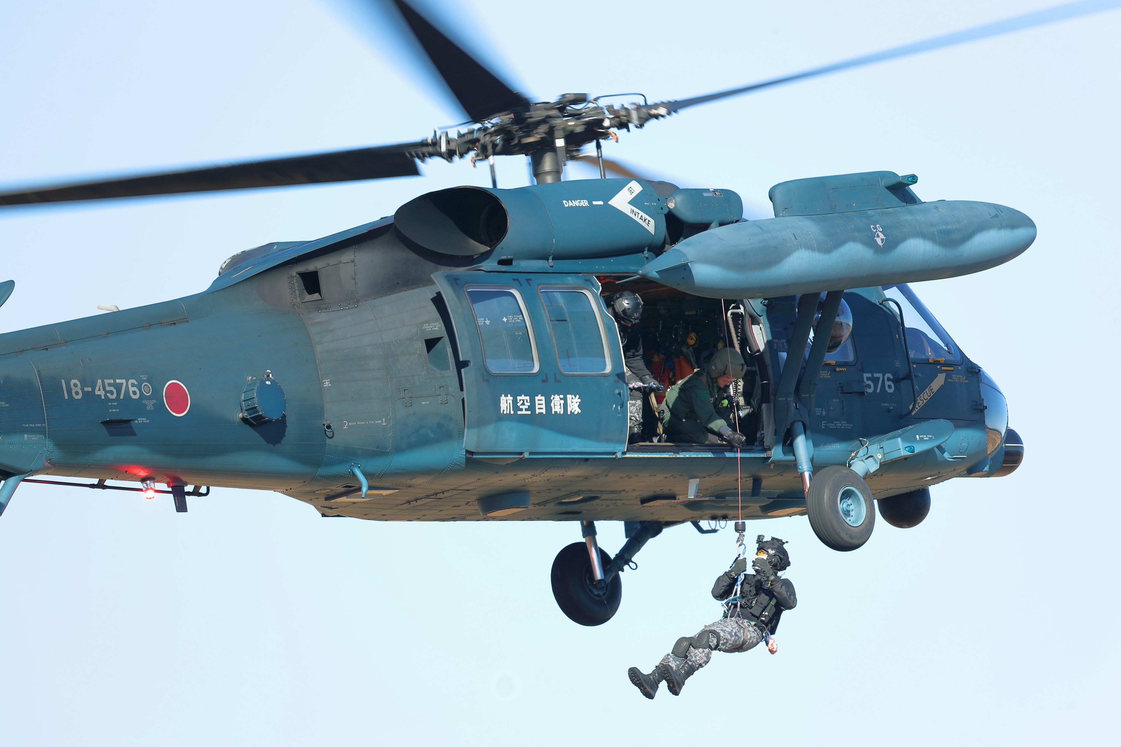 Soldat, der von einem blauen Hubschrauber an einem Seil absteigt