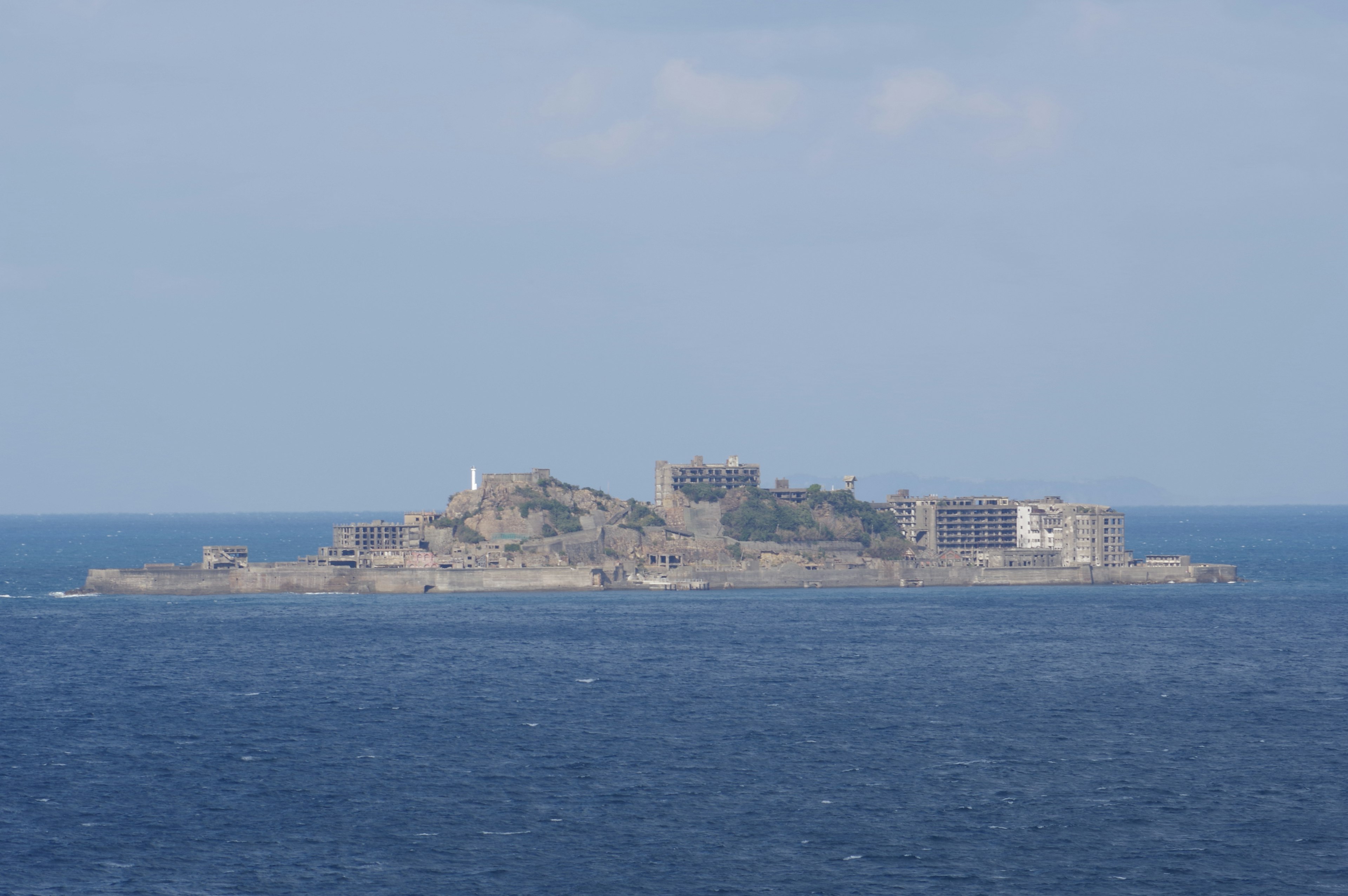 Distant view of an island featuring historical buildings under a blue sky