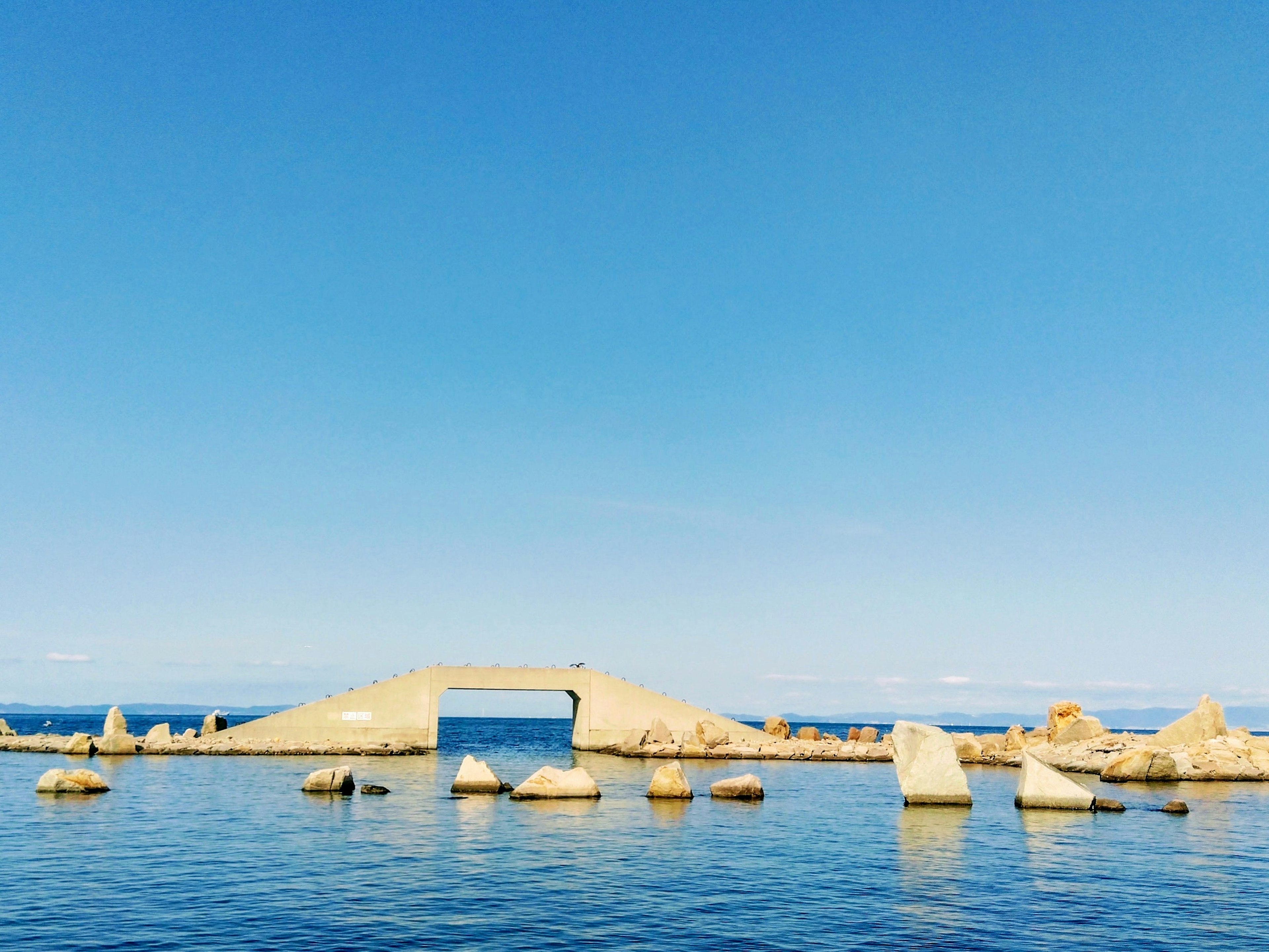 青い空と穏やかな海に浮かぶ岩のアーチ