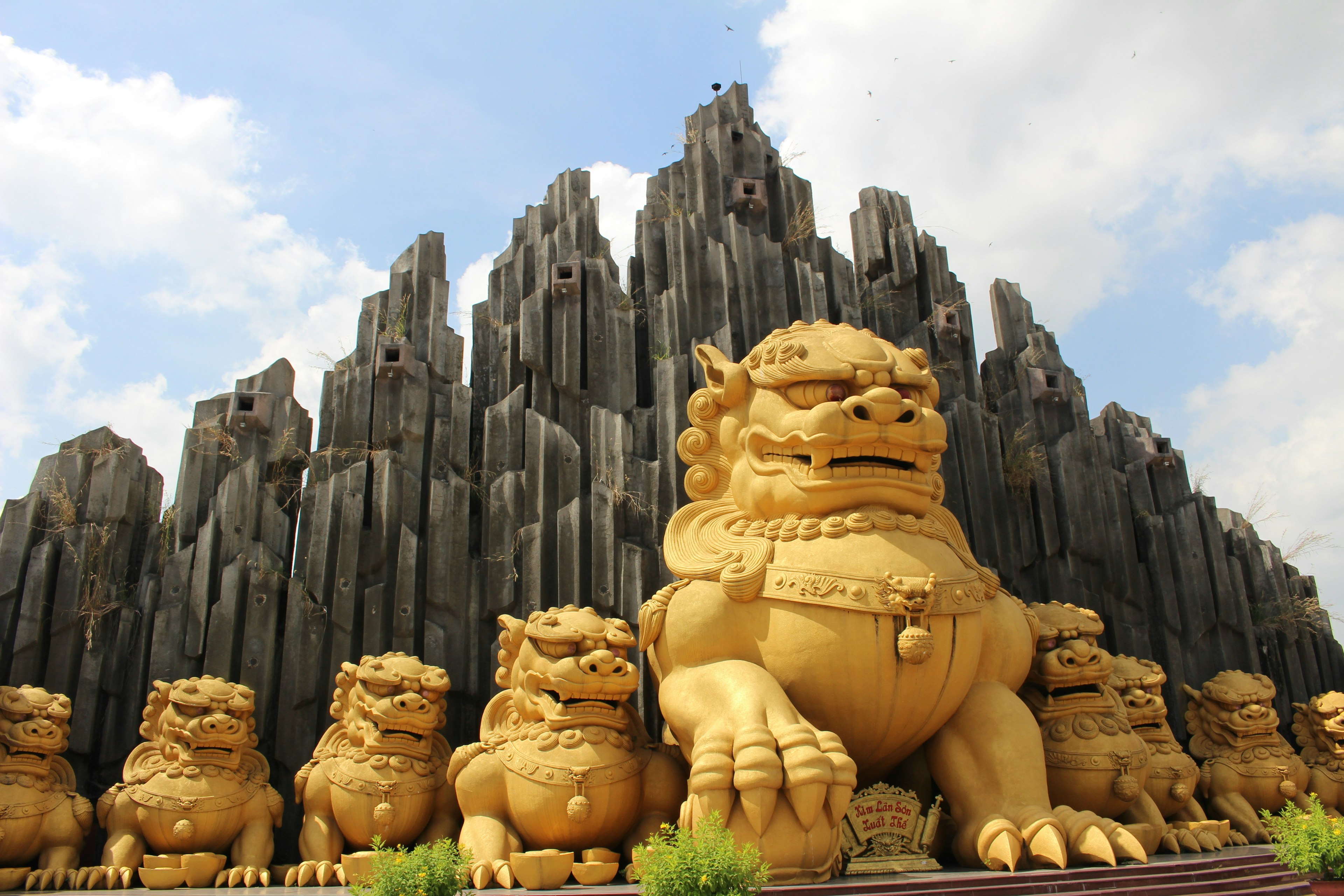 巨大な金色の獅子像が並んでいる背景に壮大な岩の山がそびえ立つ風景