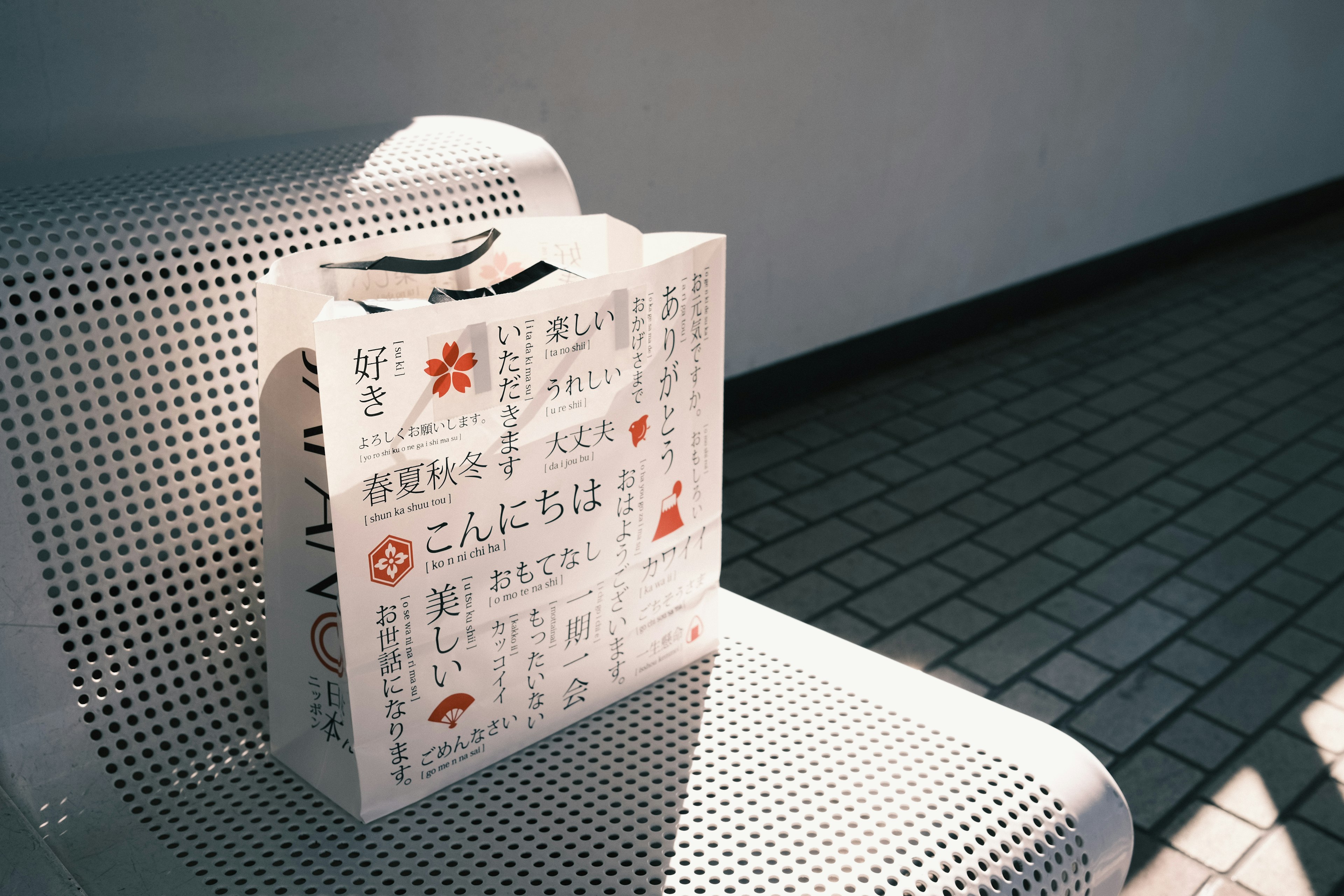 A white bag with Japanese text resting on a bench