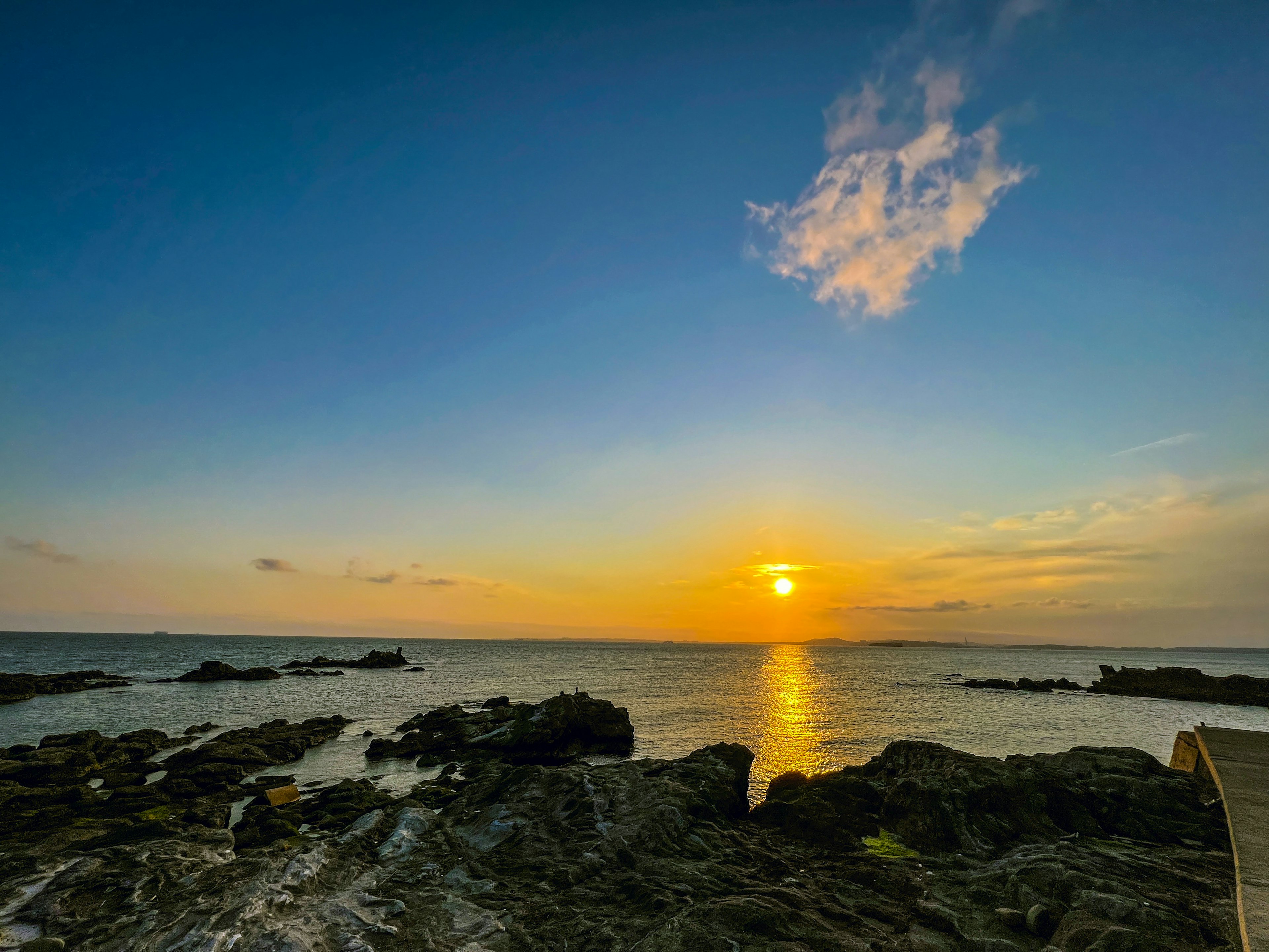 美丽的海上日落，前景有岩石