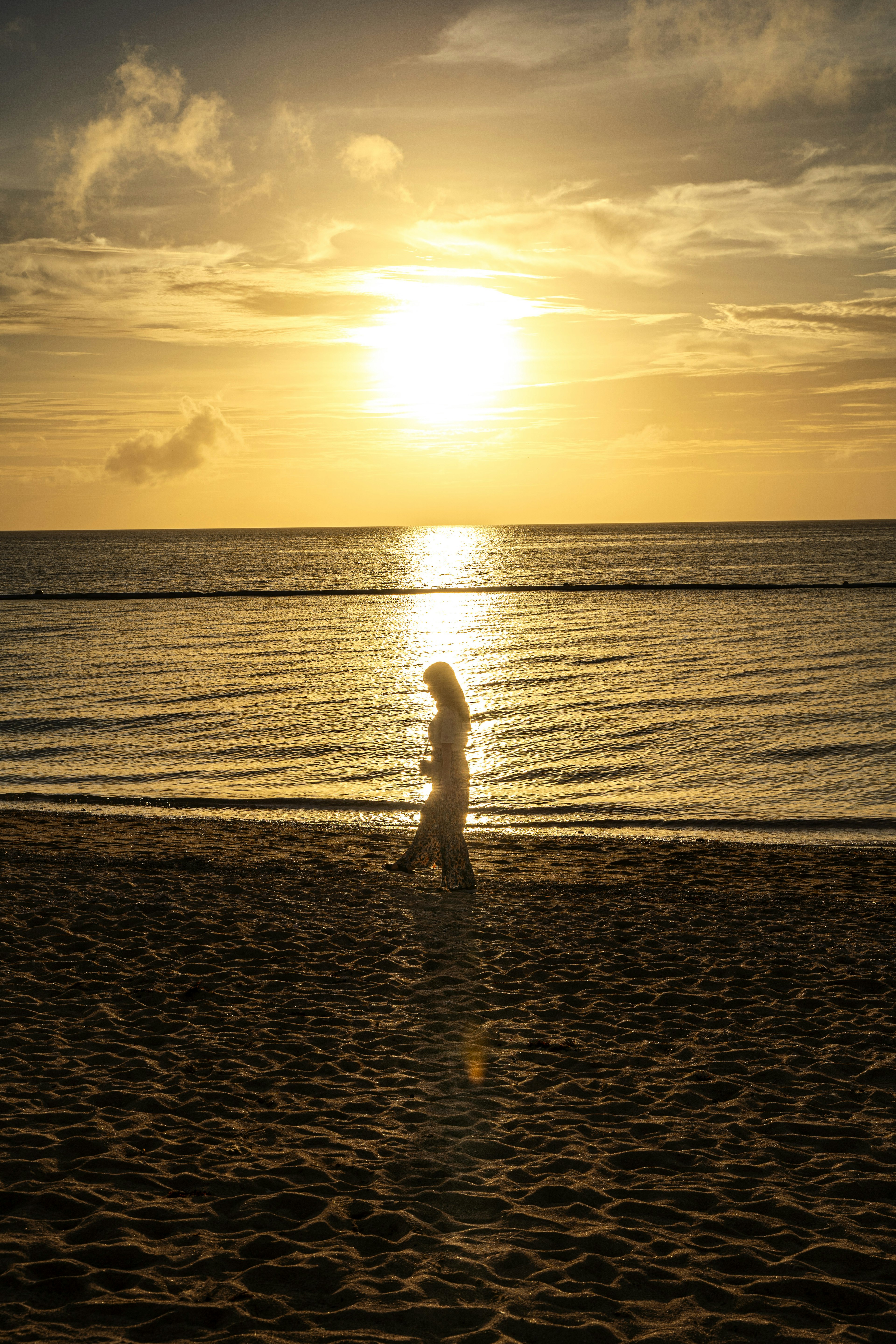 夕阳下沿海滩散步的女性剪影